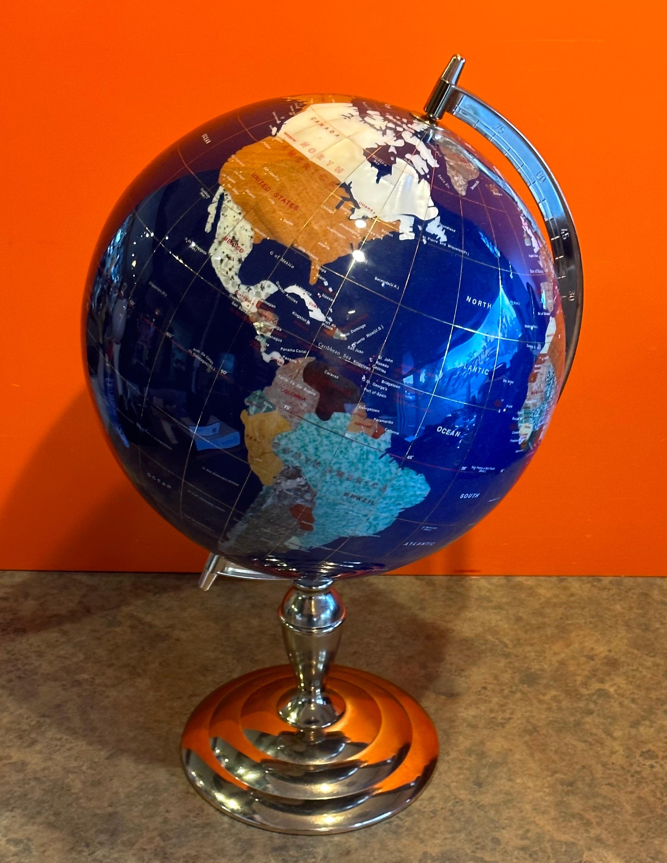 Post-modern lapis and gemstone revolving world globe on brass stand, circa 1990s.  This gorgeous globe is made of various gemstones that are perfectly cut and inlaid to form contents and countries from around the world.  The piece is in very good