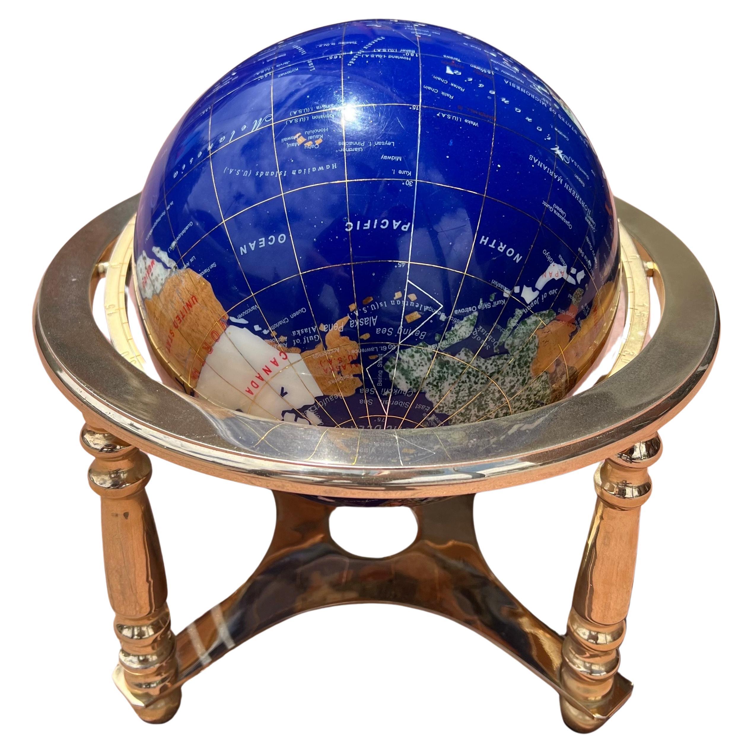 Post-modern lapis and gemstone revolving world globe on brass stand, circa 1990s.  This gorgeous globe is made of various gemstones that are perfectly cut and inlaid to form contents and countries from around the world.  The piece is in very good
