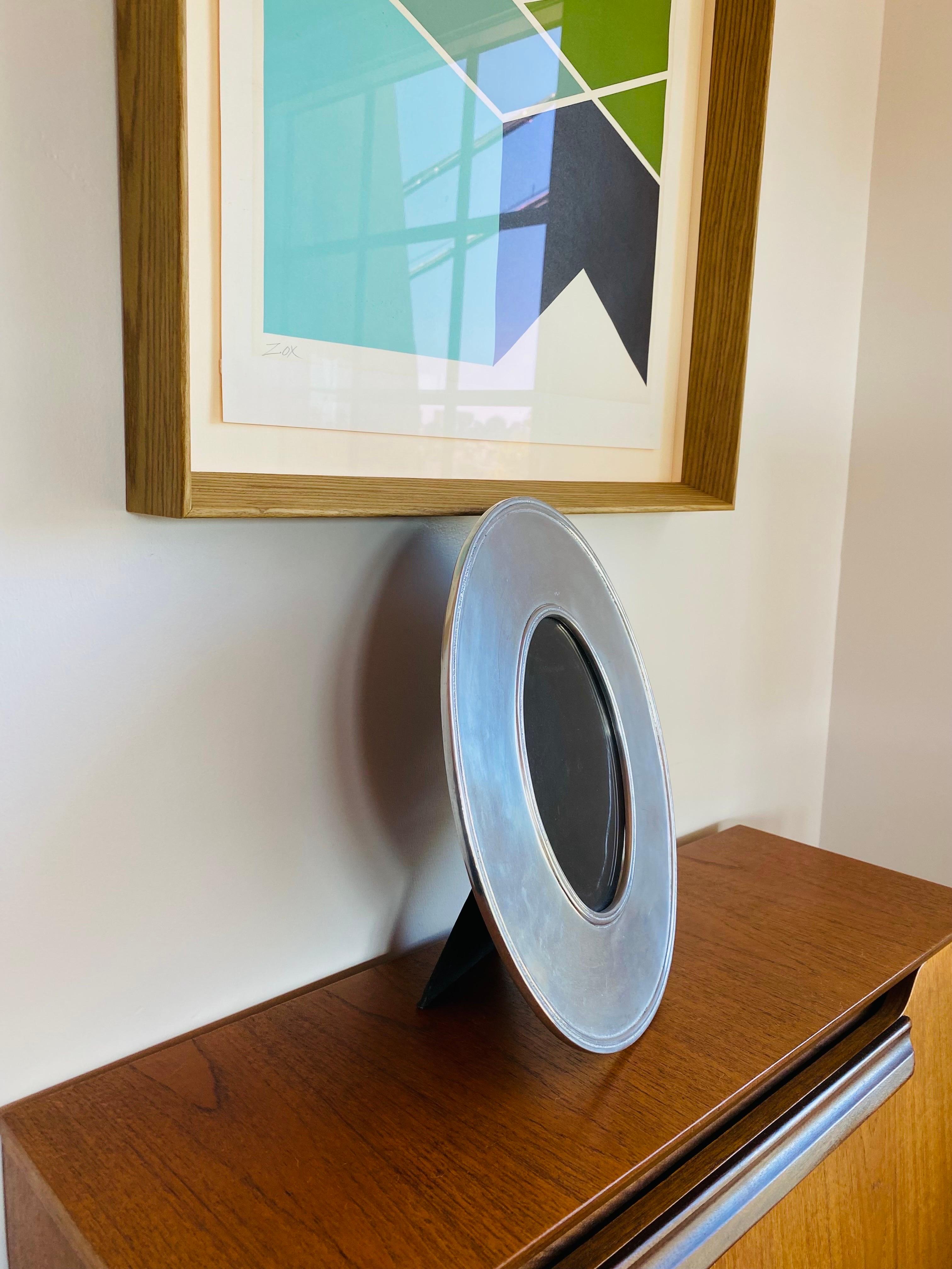 Stylish and architectural silver plated oval photo frame.  This piece inspires with legacy in design with architectural details.  This piece adds minimalist style with high impact.  The oval shape transcends into sculpture framing your treasured