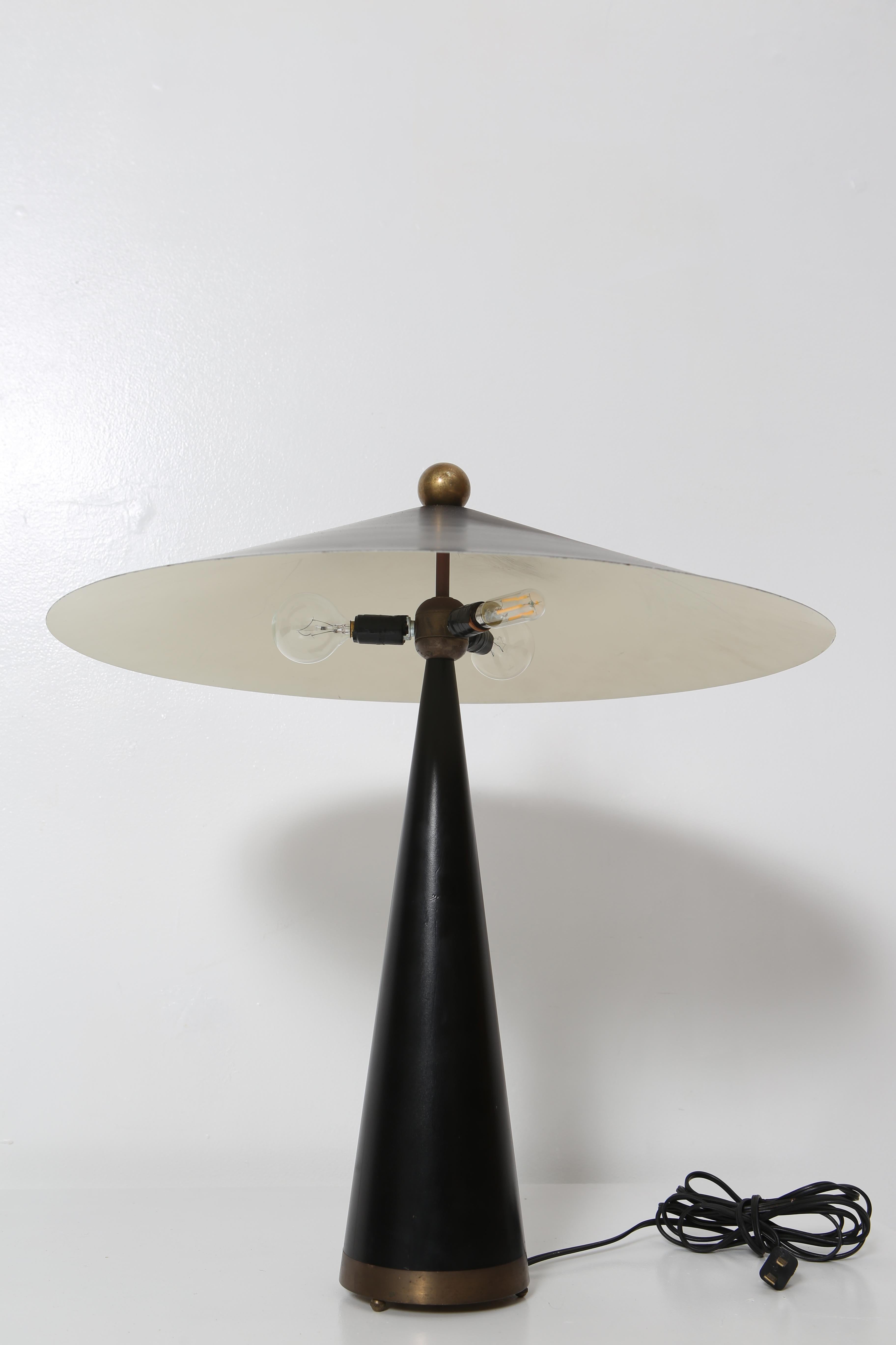 Striking table lamp in conical form; constructed of a substantial solid brass base, wrapped in leather, triple candelabra sockets under a spun steel lacquered shade. Oversized ball finial of solid brass. Handmade in Santa Cruz, CA 1988, “Johnson