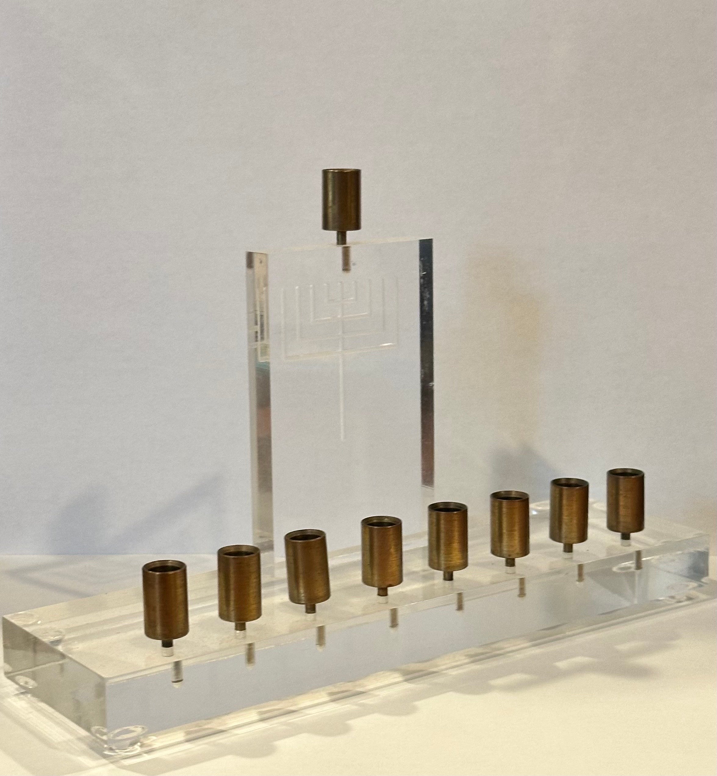 Magnifique menorah post-moderne en lucite et laiton, vers les années 1980.  La pièce est composée d'une base et d'un dos en lucite gravée avec des récipients en laiton pour les bougies. La ménorah est en très bon état, sans éclats ni fissures, et