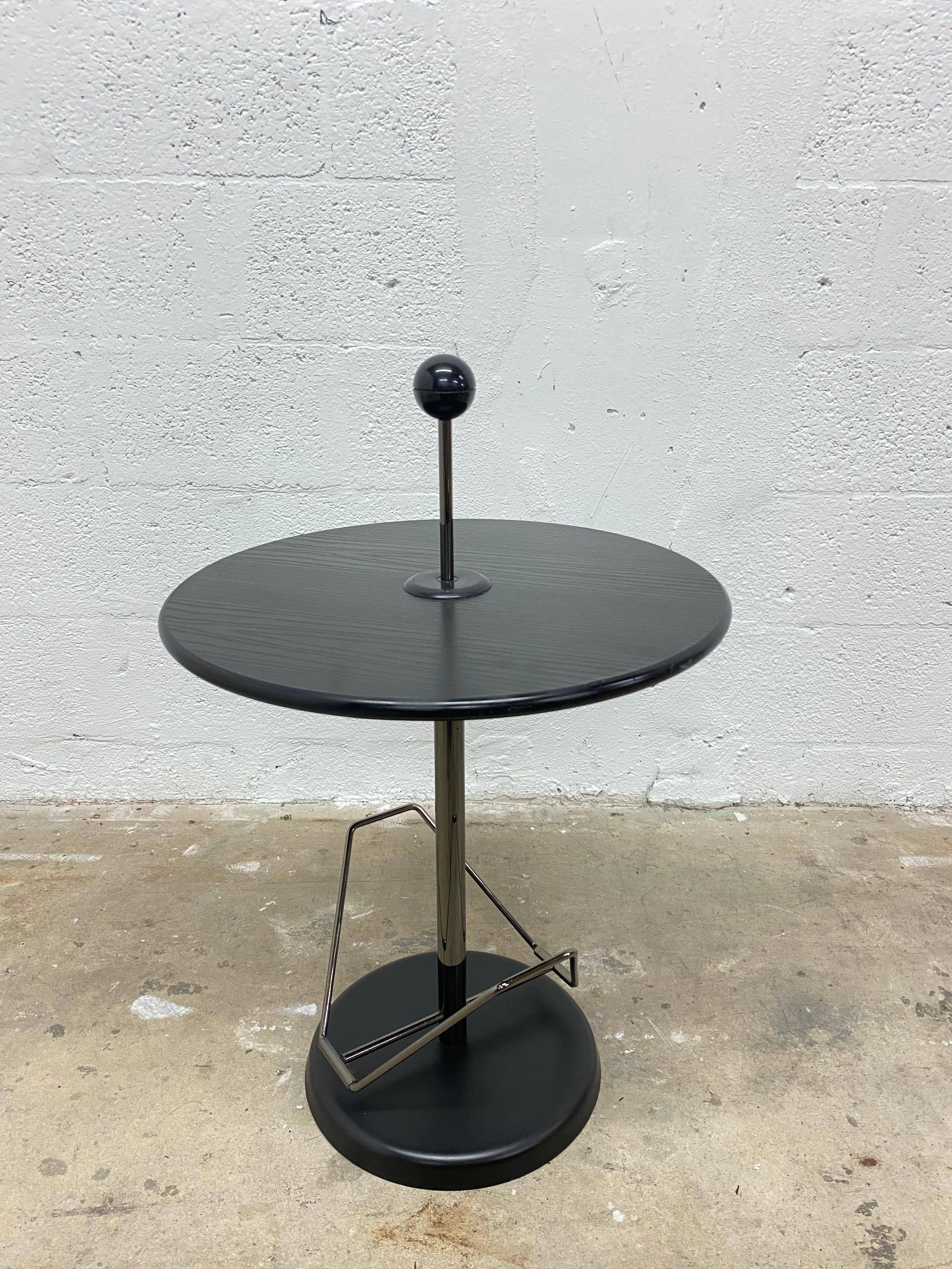 Circular, post-modern contemporary black side table with tubular gunmetal steel magazine holder and center shaft with knob from the 1980s.