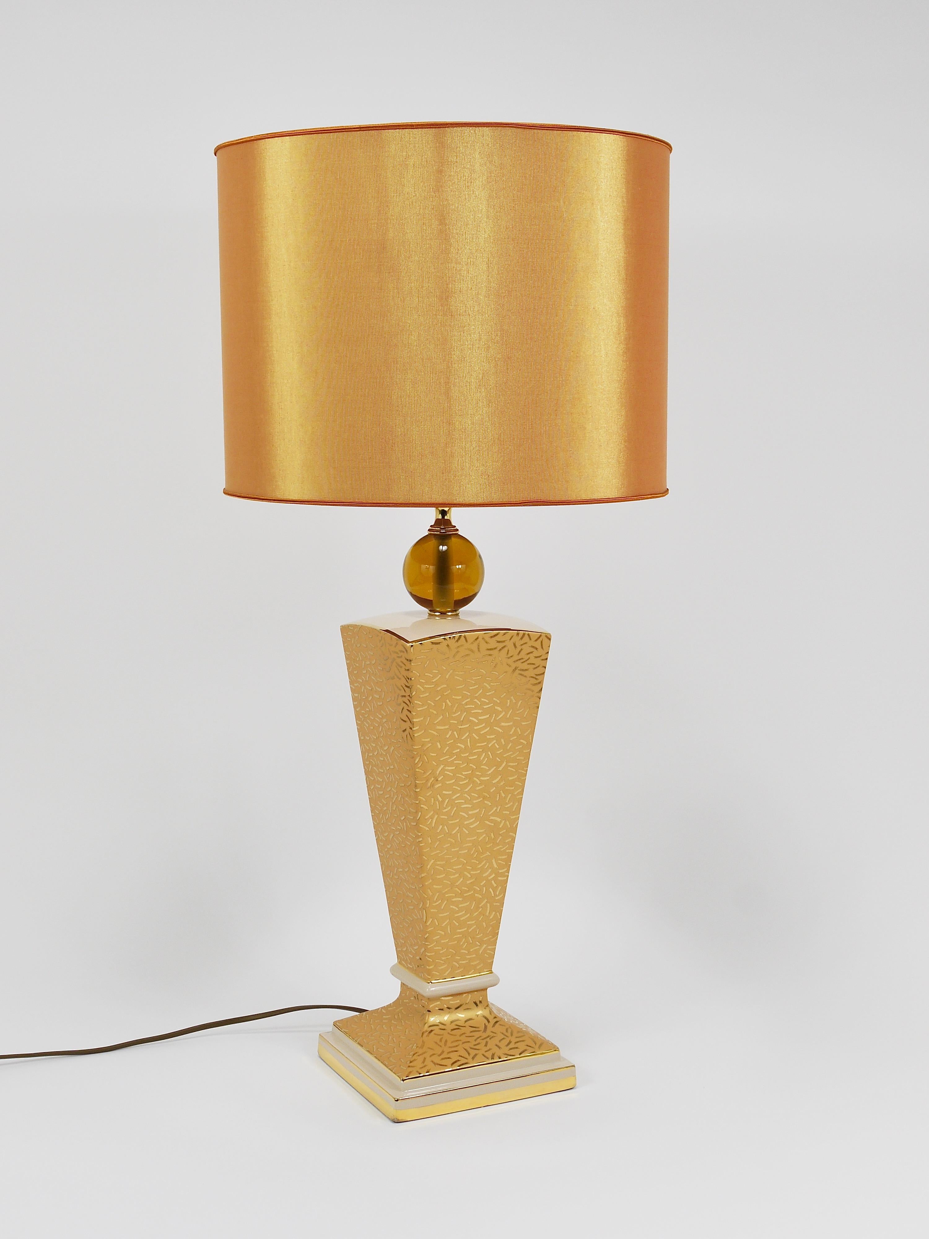 A beautiful and decorative postmodern Art Deco-style table or side lamp from the 1980s, made in Italy. The lamp’s base is crafted from porcelain with a beige glaze and features stunning golden Memphis-style patterns and embellishments. It comes with