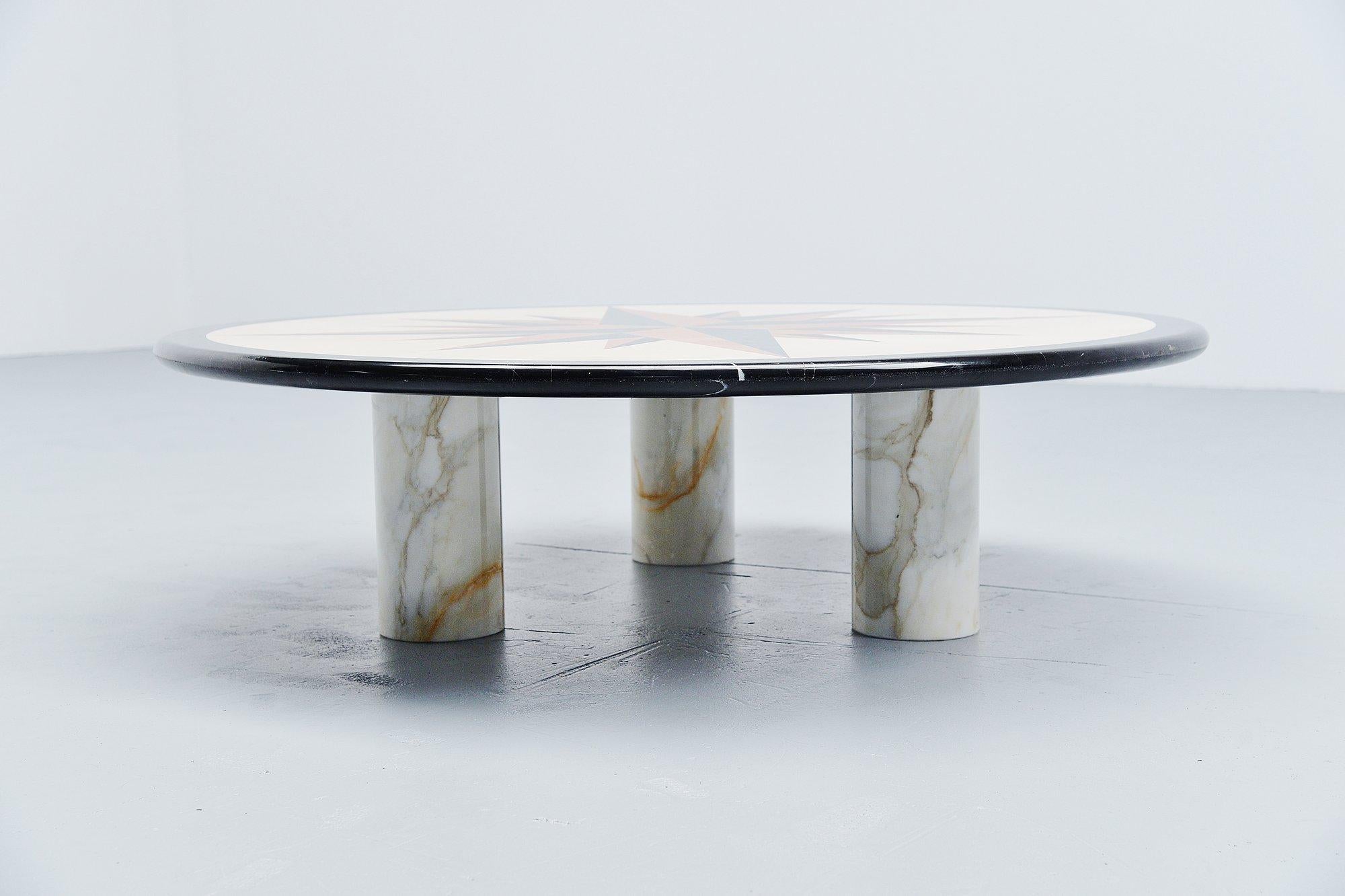 Fantastic and extremely heavy post modern coffee table made in the Memphis period, Italy 1980. This table has a fantastic shaped marble inlayed top with different colors and types of marble. Three cylindrical solid marble feet support the heavy