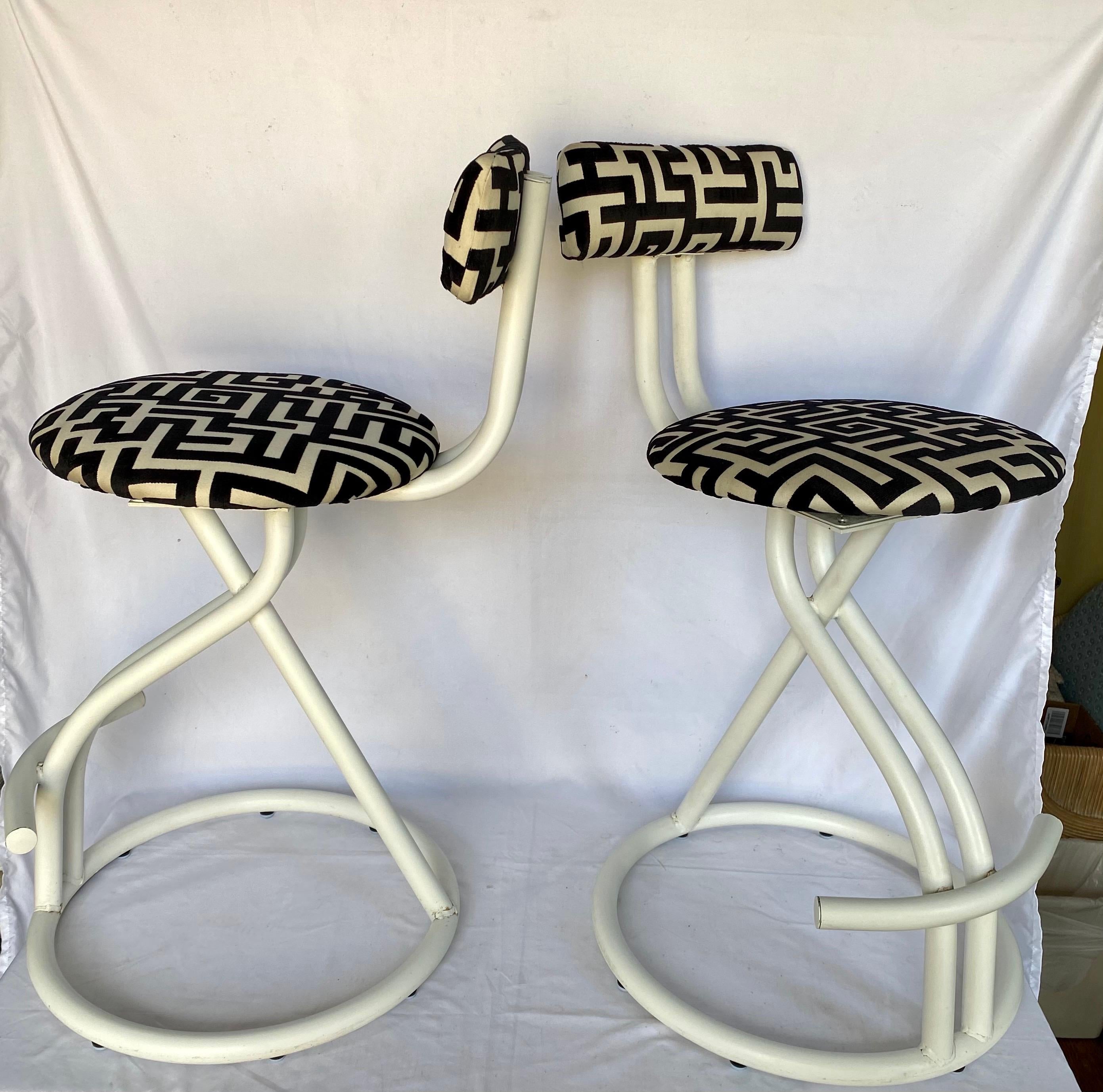 Pair of post modern Memphis Milano style swivel stools by Cal-Style. These sculptural counter bar stools feature cream powder coated tubular frames and have been professionally reupholstered in a luxurious graphic Jim Thompson Greek key inspired cut