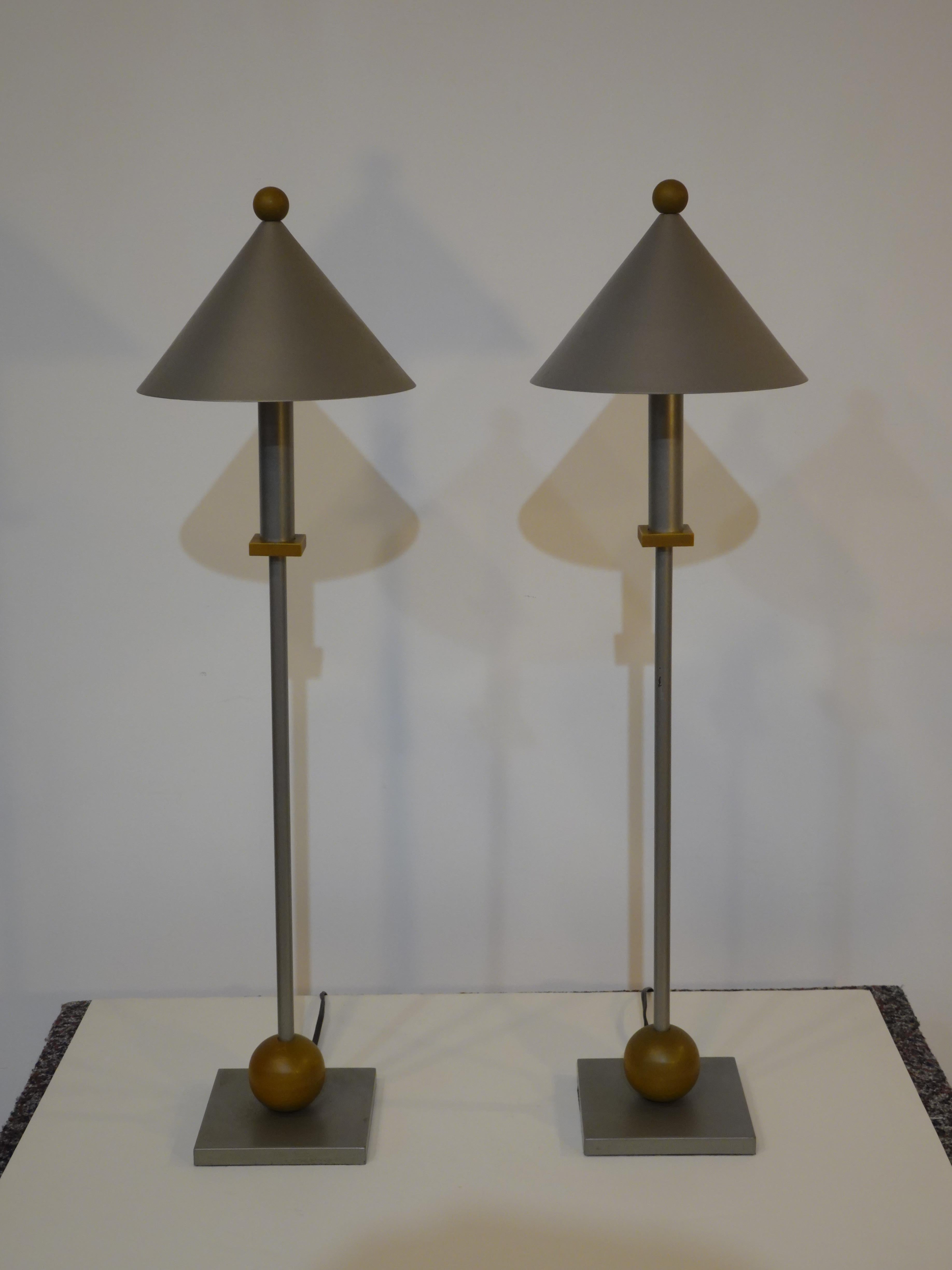 A pair of pewter toned metal table lamps with coned shades topped with patinaed brass finals matching the ball to the base and middle detail piece. Inside the shade is a frosted glass defuser so the light is a bit softer and even with a in line on