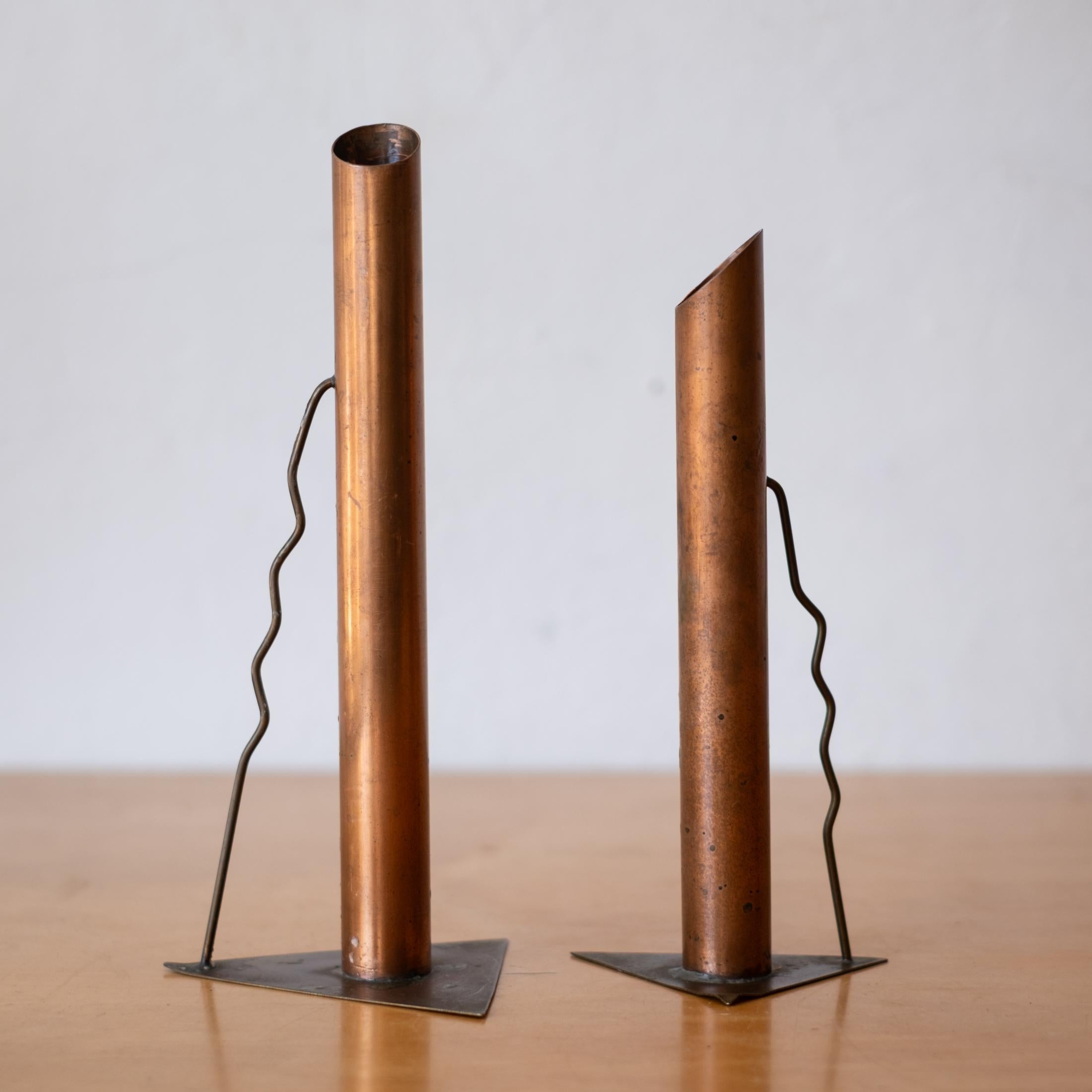 Una coppia di bastoni per candele in rame realizzati da un artista post-moderno negli anni '80. Il rame ha una patina calda che completa le linee e le forme eleganti. Ogni supporto è costituito da un tubo di rame alto e cilindrico con la parte