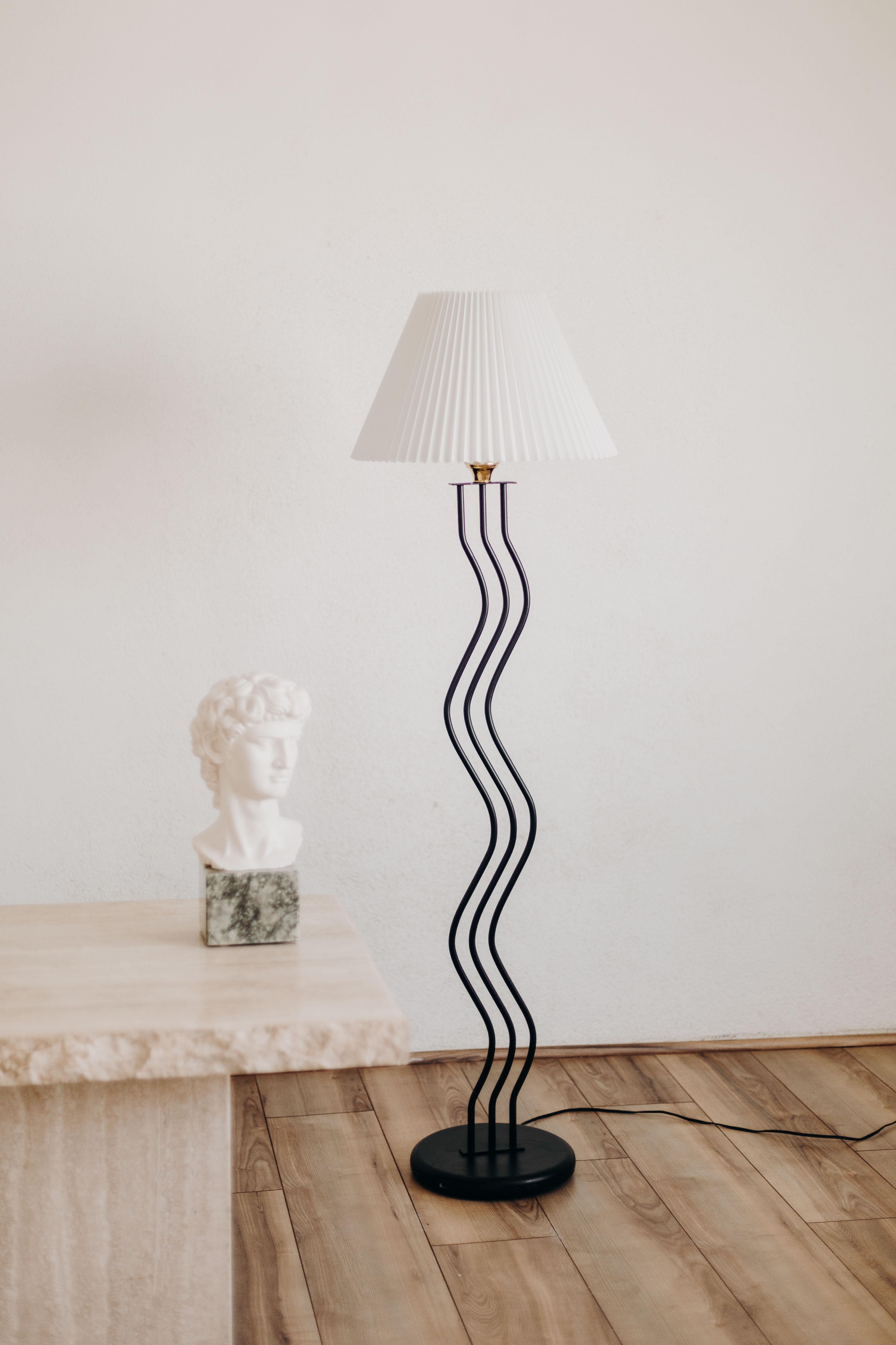 The vintage post-modern Memphis style floor lamp from the 1980s is a striking piece of furniture that showcases the best of bold design and playful aesthetics. The lamp's wave design is not only fun and current, but it is also a reflection of the