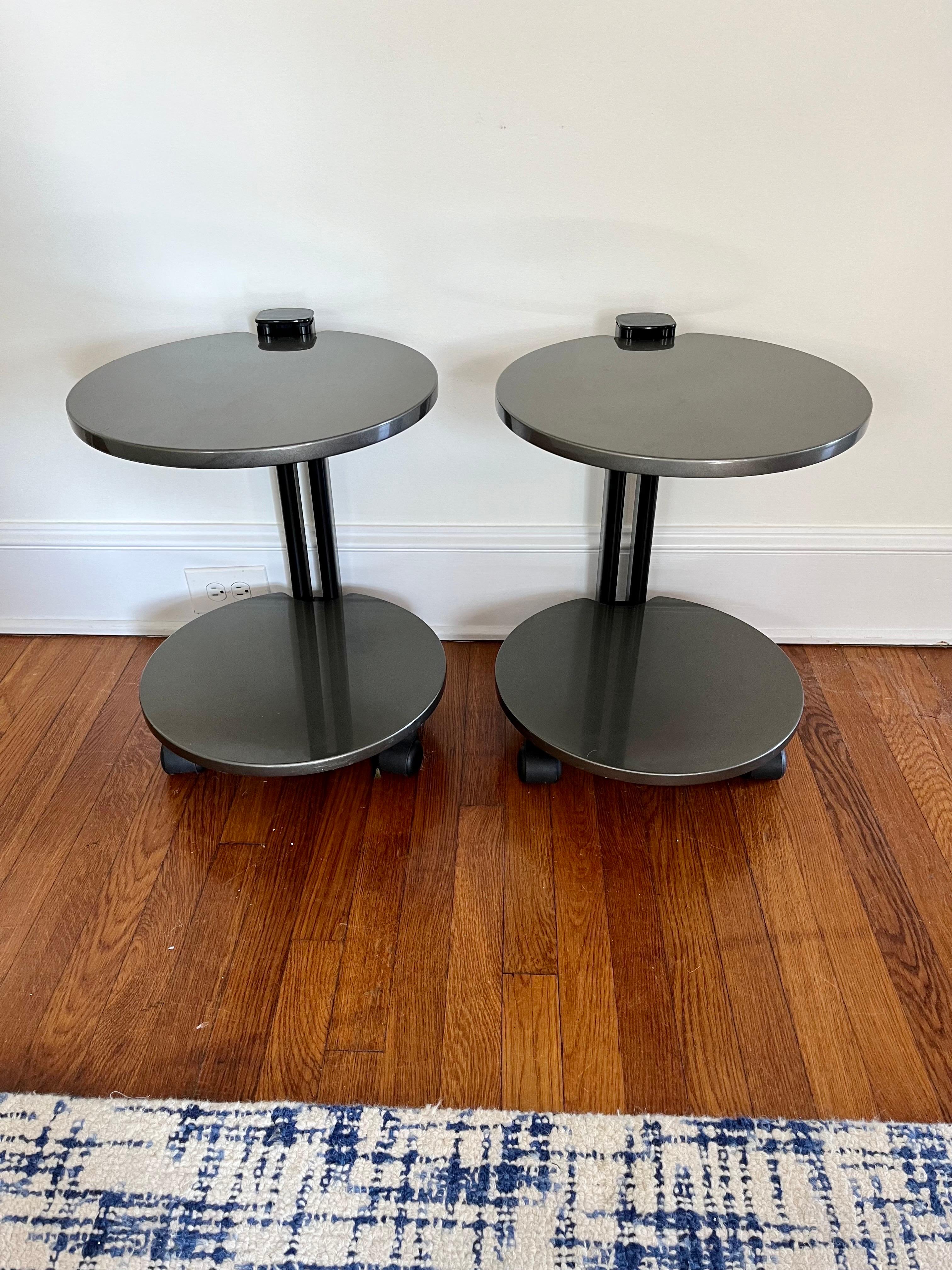 Post-Modern mixed media two tier side table, the round top and lower tier suspended by a column support. Lacquer metal surfaces with matte black supports. 2 casters and one stationary support to allow in place pivoting. 
Curbside to NYC/Philly $350