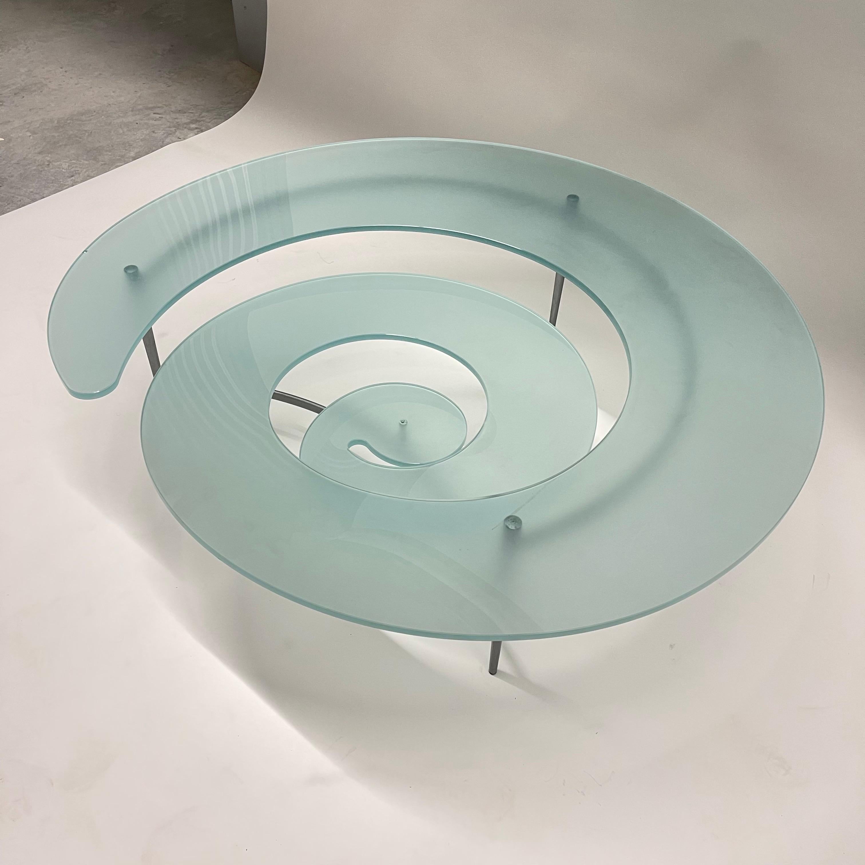 Post-Modern sculptural nautilus spiral coffee or cocktail table rendered in sandblasted cut and bent glass with a titanium powder coated steel tripod frame, by Cattelan Italia, Italy, 1990's.