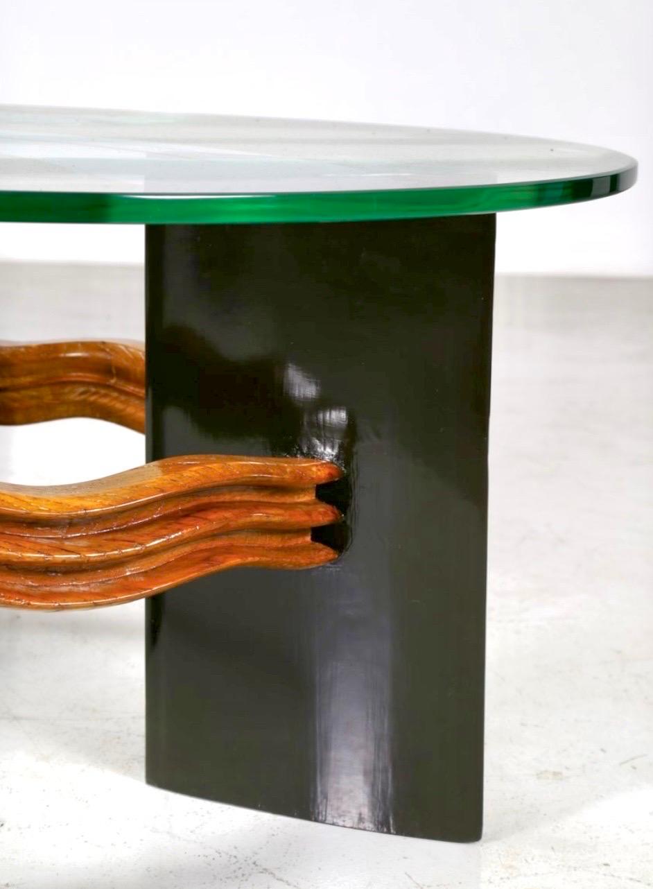 Superbe table à cocktail Osvaldo Borsani du maître italien, dotée d'un épais verre transparent circulaire reposant sur des panneaux architecturaux reliés par un exquis châssis ondulé, profondément sculpté à la main avec un savoir-faire remarquable. 