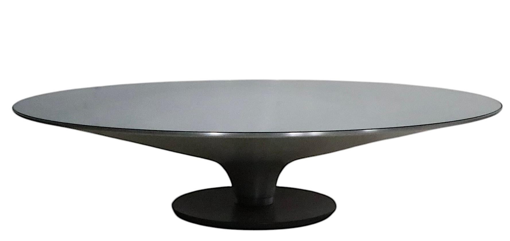Chic architectural coffee, cocktail table Ovni  designed by Vincenzo Maiolino for Roche Bobois. The table features a dramatic  trumpet form  base constructed of spun aluminum, on a cast metal base, with a tempered glass insert top. This example is