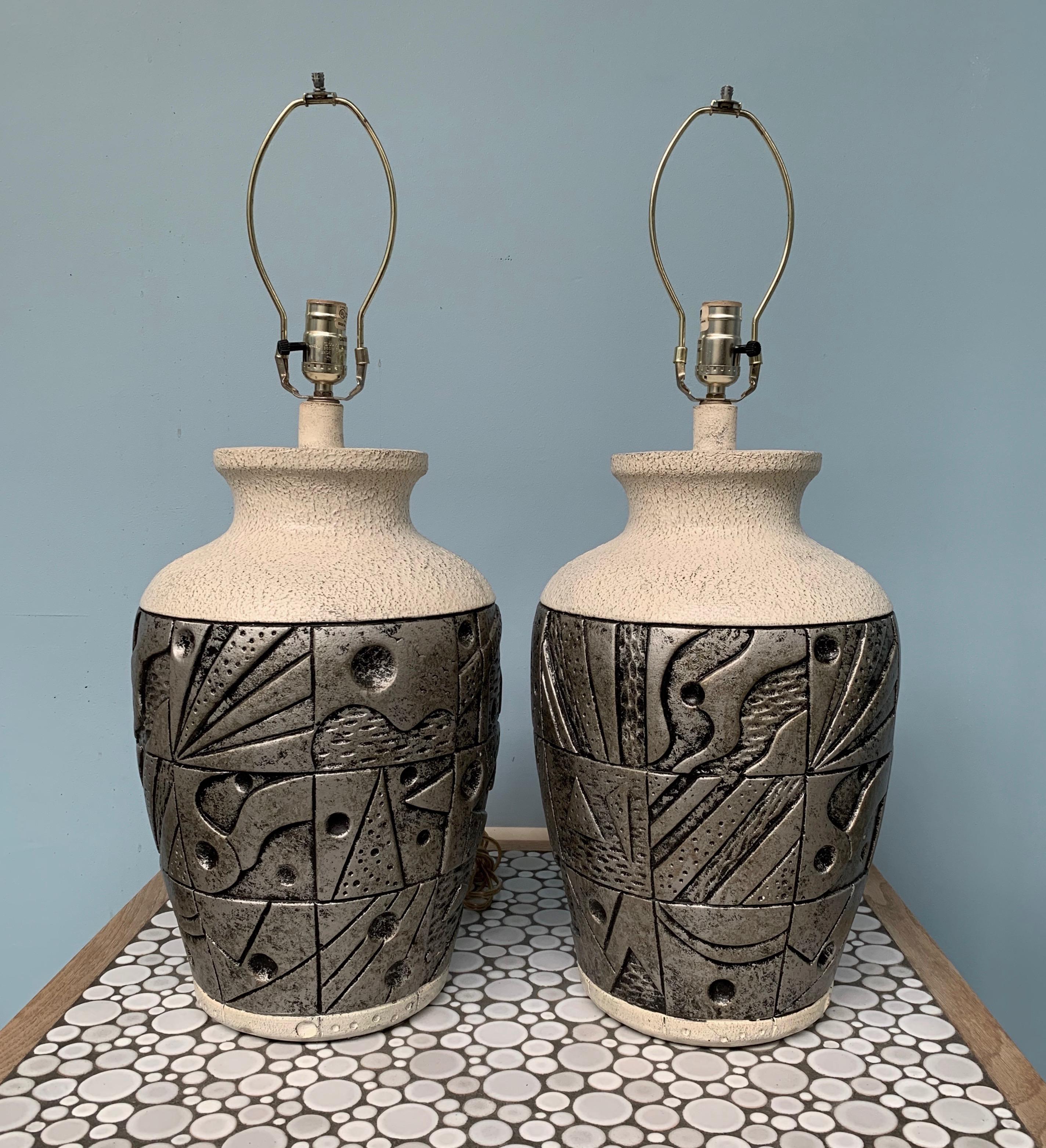 A pair of lamps by Everlasting Lamps of Sun Valley Ca. produced in chalk has a base relief sculptural decoration.