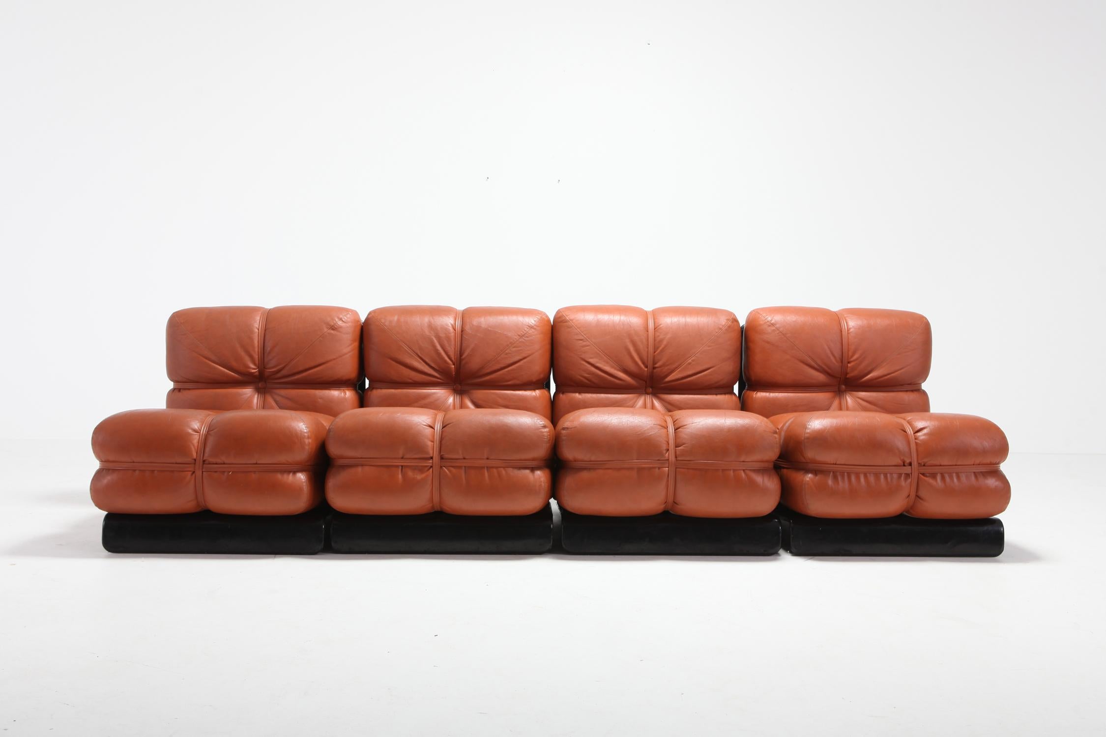 Cognac leather sectional sofa with black lacquered wooden frame by Carla Venosta.
The piece consists out of 4 lounge chairs unattached to create a sofa.

Carla Venosta was a designer and decorator for the beau monde in the 1980s.


