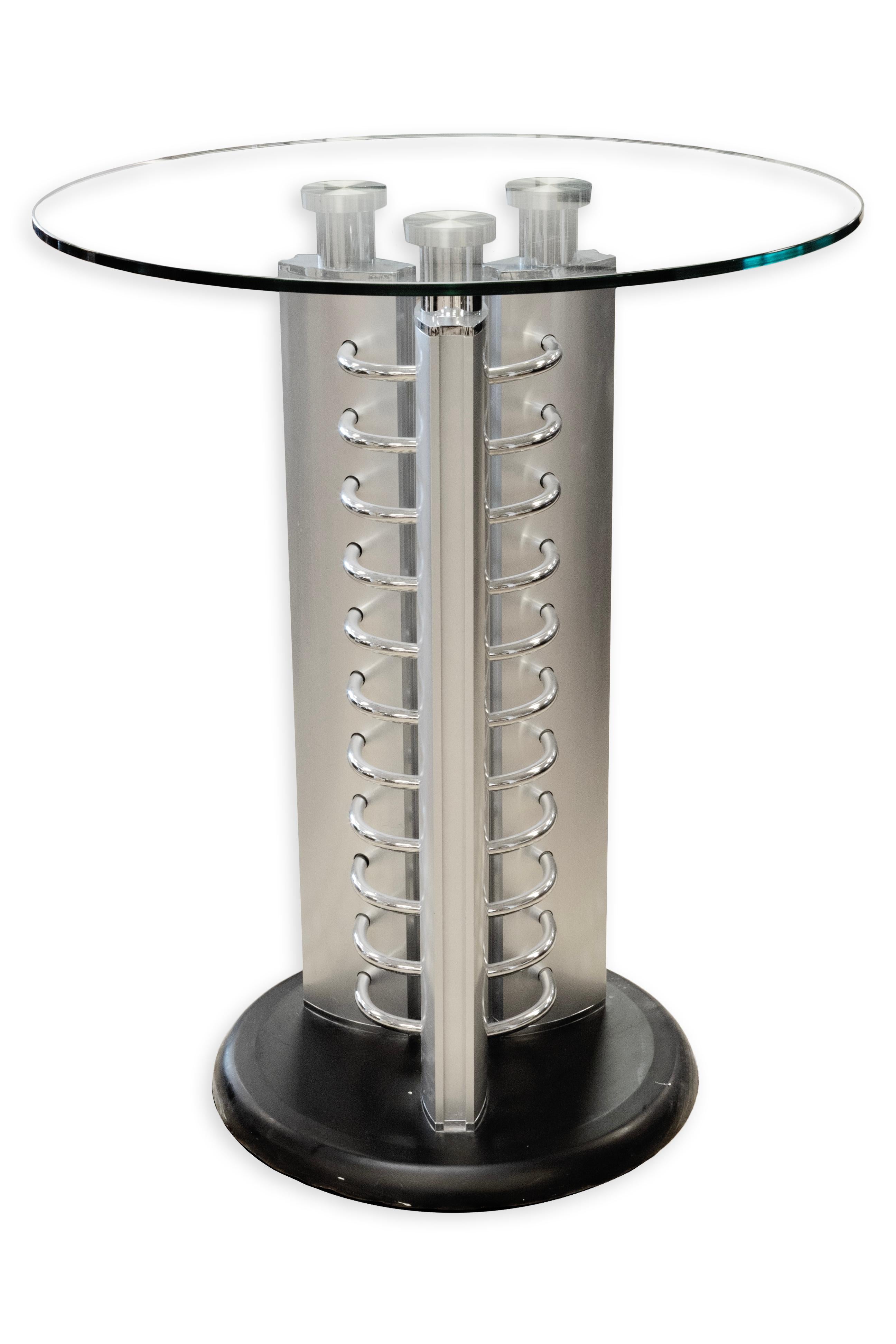 Questo tavolino rotondo postmoderno in vetro e metallo con dettagli cromati incarna un'estetica audace e architettonica. Il piano in vetro trasparente offre una superficie pulita e moderna, mentre lo scultoreo piedistallo in metallo è arricchito da