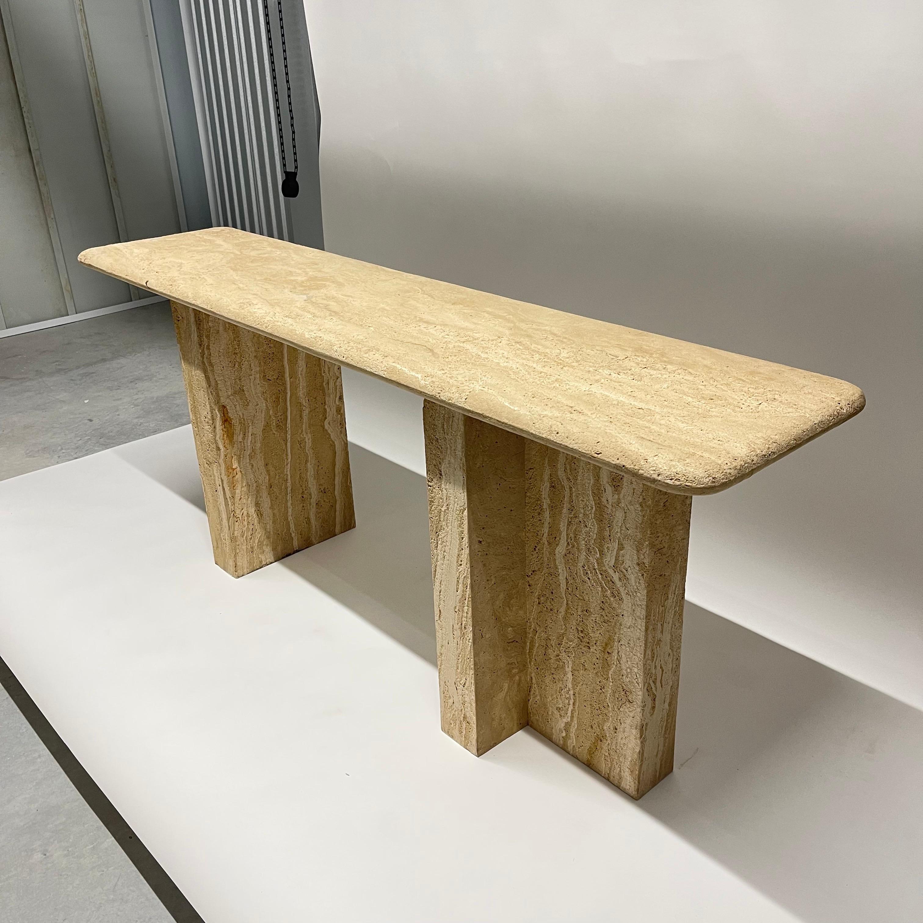 Unique post-modern console or sofa table rendered in sandblasted travertine with two T from pedestal bases and a bullnose top, finished on all sides in the style of Angelo Mangiarotti, Italy, circa 1980's.