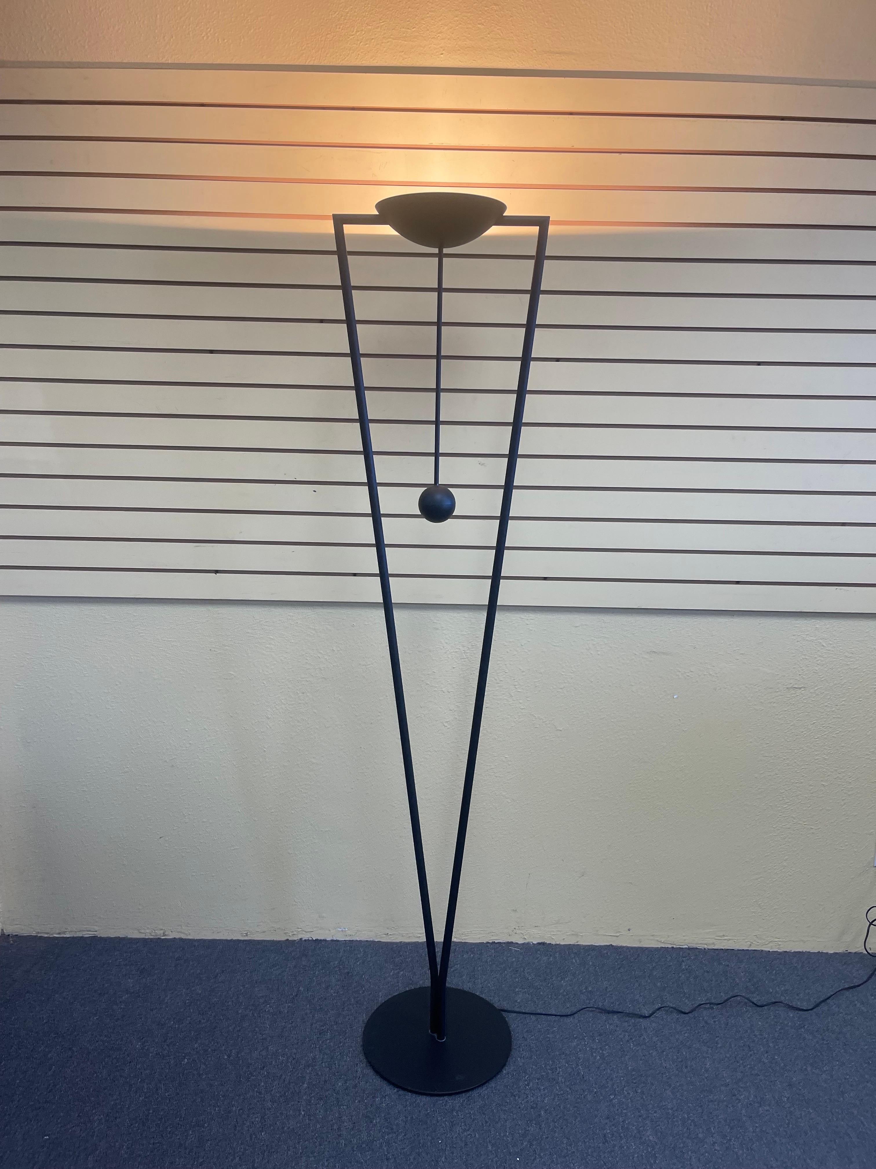 Post-modern sculptural multi-directional floor lamp by Ron Rezek, circa 1980s. The lamp features an adjustable head controlled by a counter-balanced extension transforming the floor lamp into a torchiere. The piece has a mat black finish and