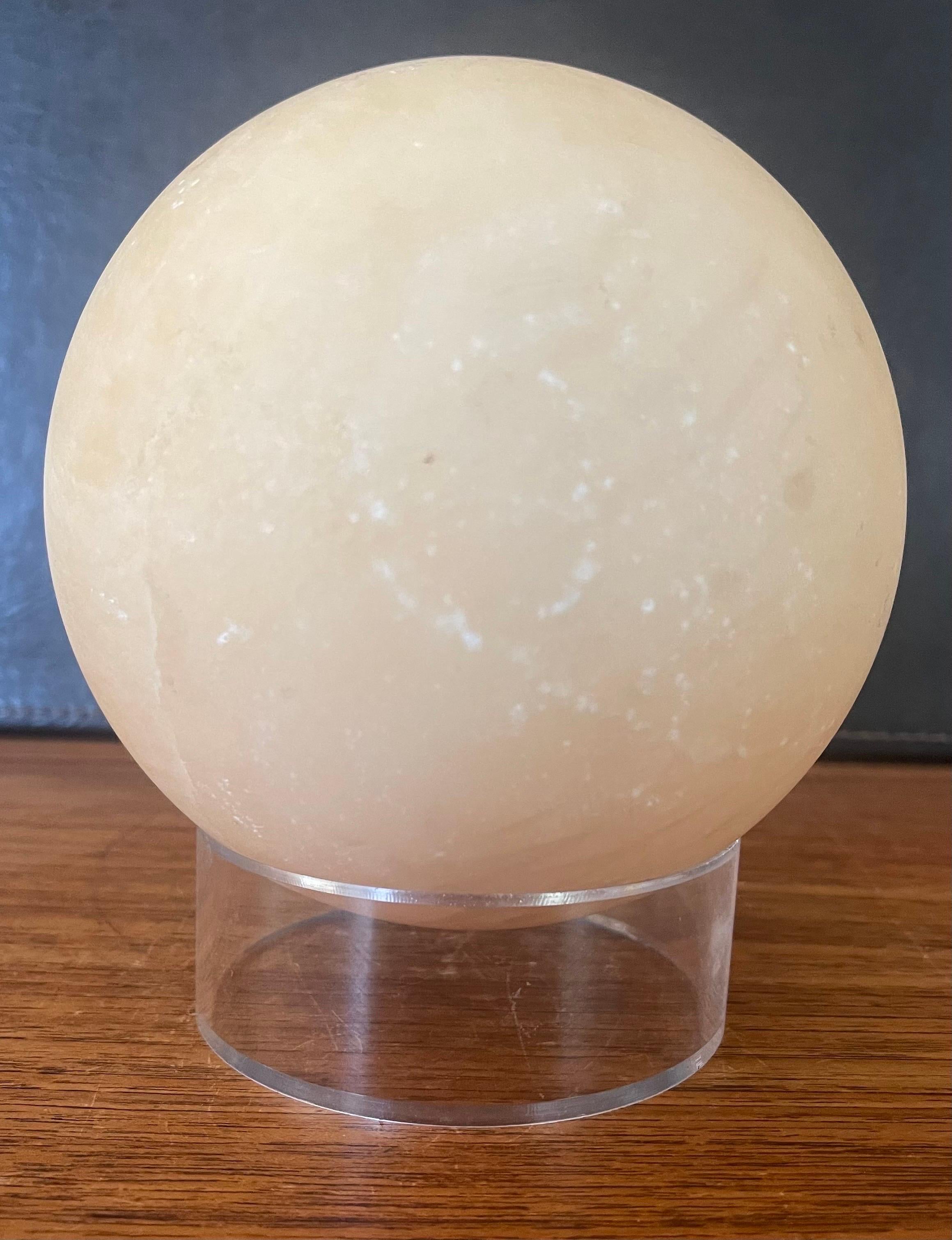 Beautiful post-modern solid polished travertine sphere on lucite ring base, circa 1980s. The sphere is in very good vintage condition and measures 5.75