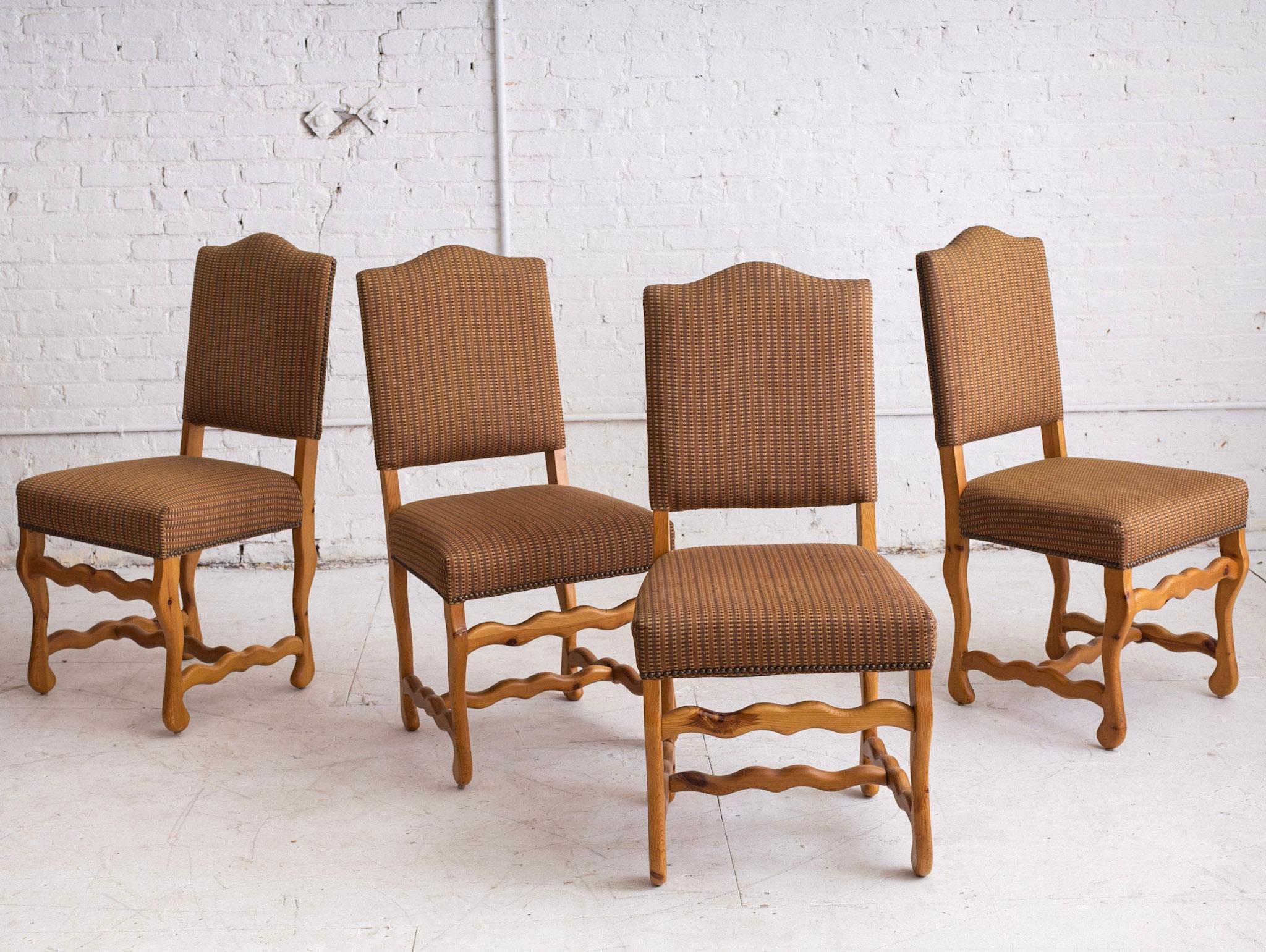 A set of 4 post modern dining chairs. A traditional silhouette in knotty pine with 'squiggle' or 'wave' form detail. Original textured brown upholstery with brad nail trim.