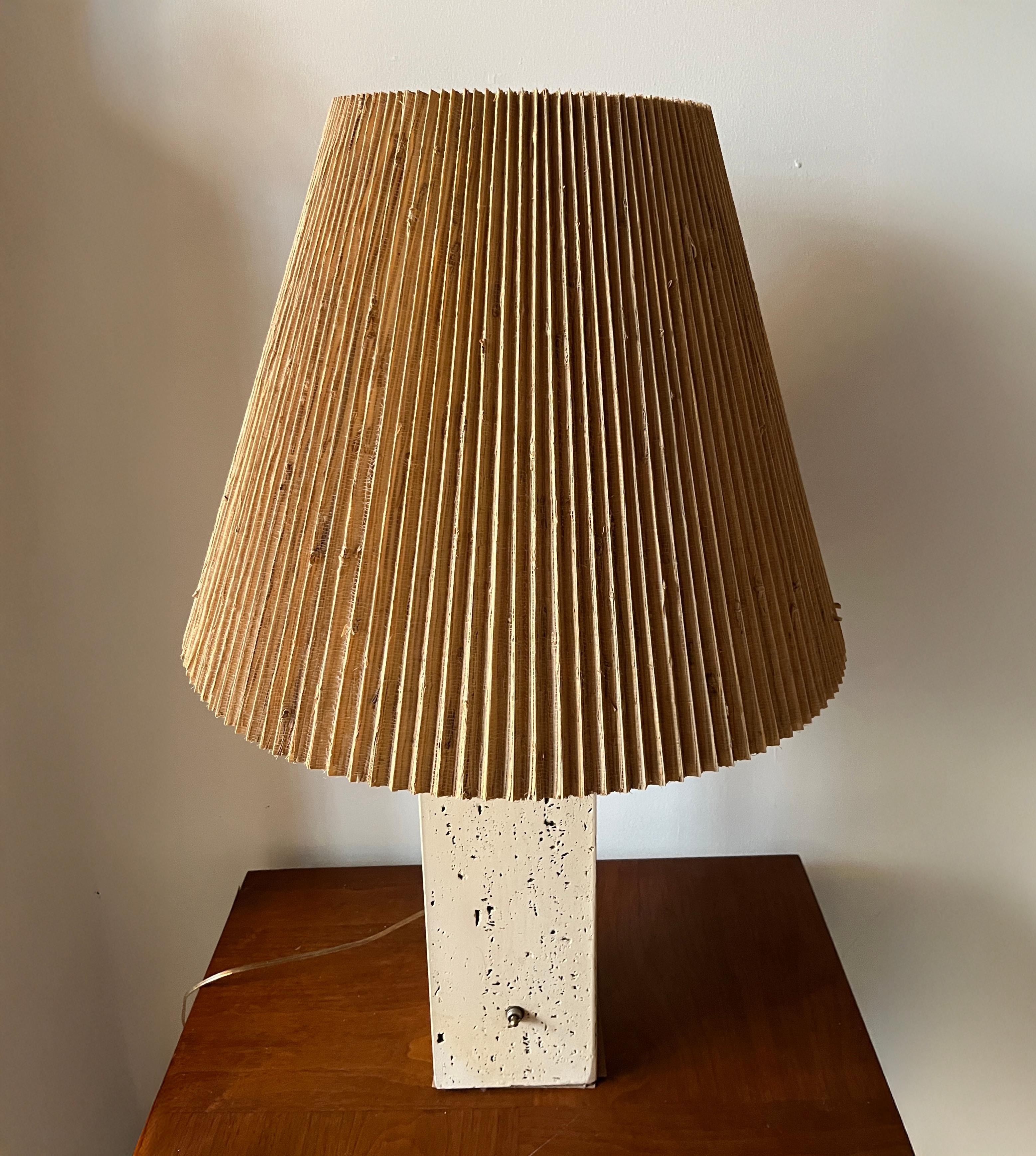 Large-scale Post-Modern table lamp in the style of George Kovacs in off-white / cream travertine in the form of a squared column. Includes original pleated sisal lampshade. 

Travertine is known for being lightweight yet strong. It has a matte, not