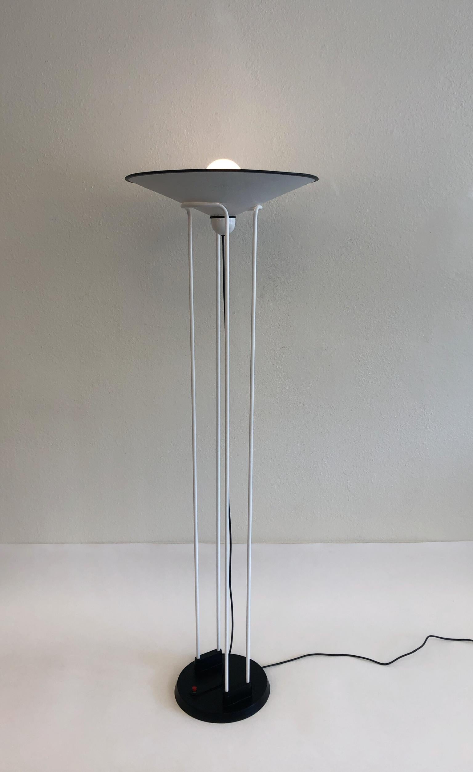 A spectacular Postmodern torchiere floor lamp design by Ron Rezek in the 1980s. The lamp is metal powder coated white and black with a red on/off switch on the base.
Dimensions: 71.75” high 24” diameter.
