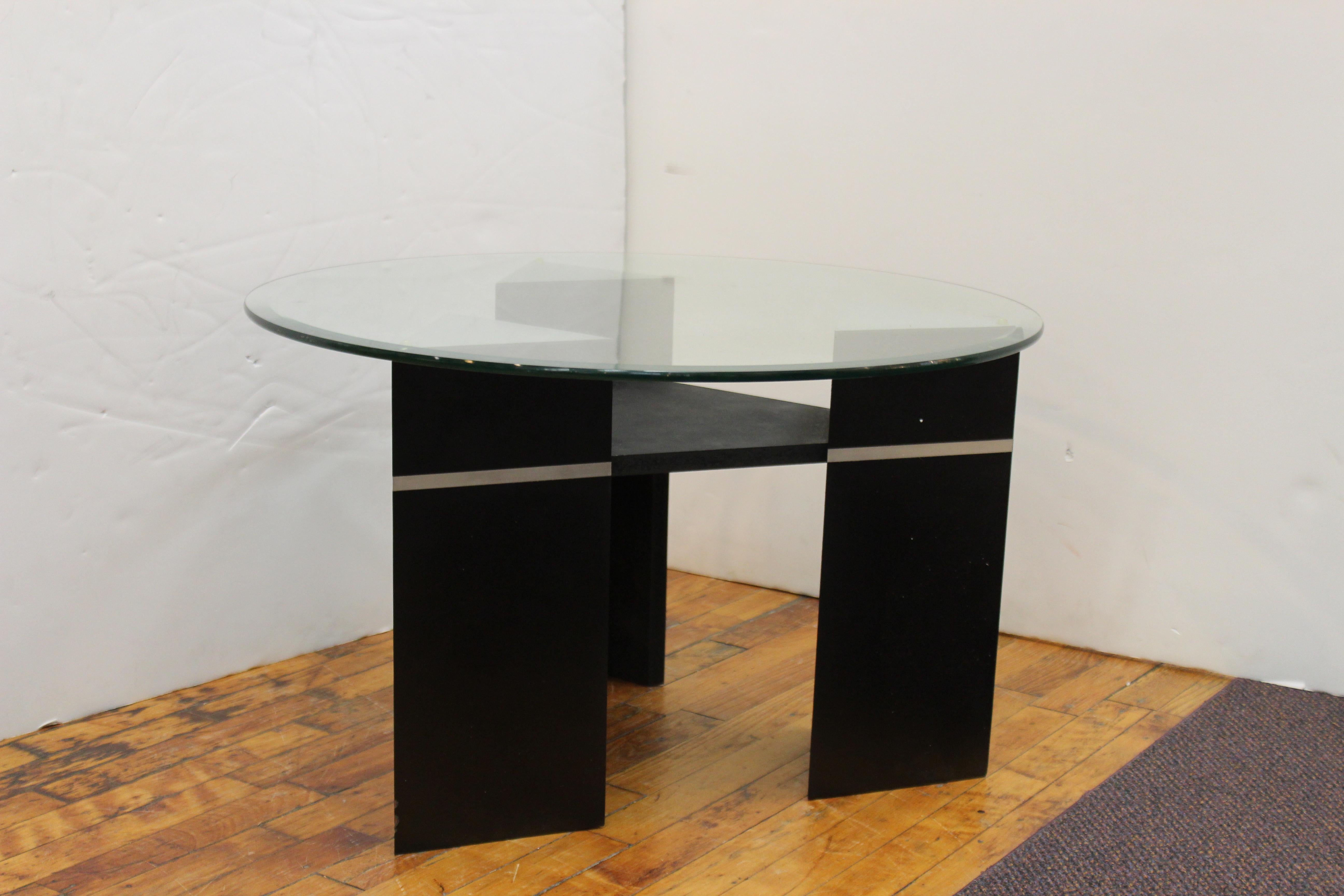Postmodern side table or coffee table in triangular shape with a round glass top. The piece has three triangular shaped legs and is painted in black with silver embellishments. Likely a custom design made in the late 20th century. In great vintage
