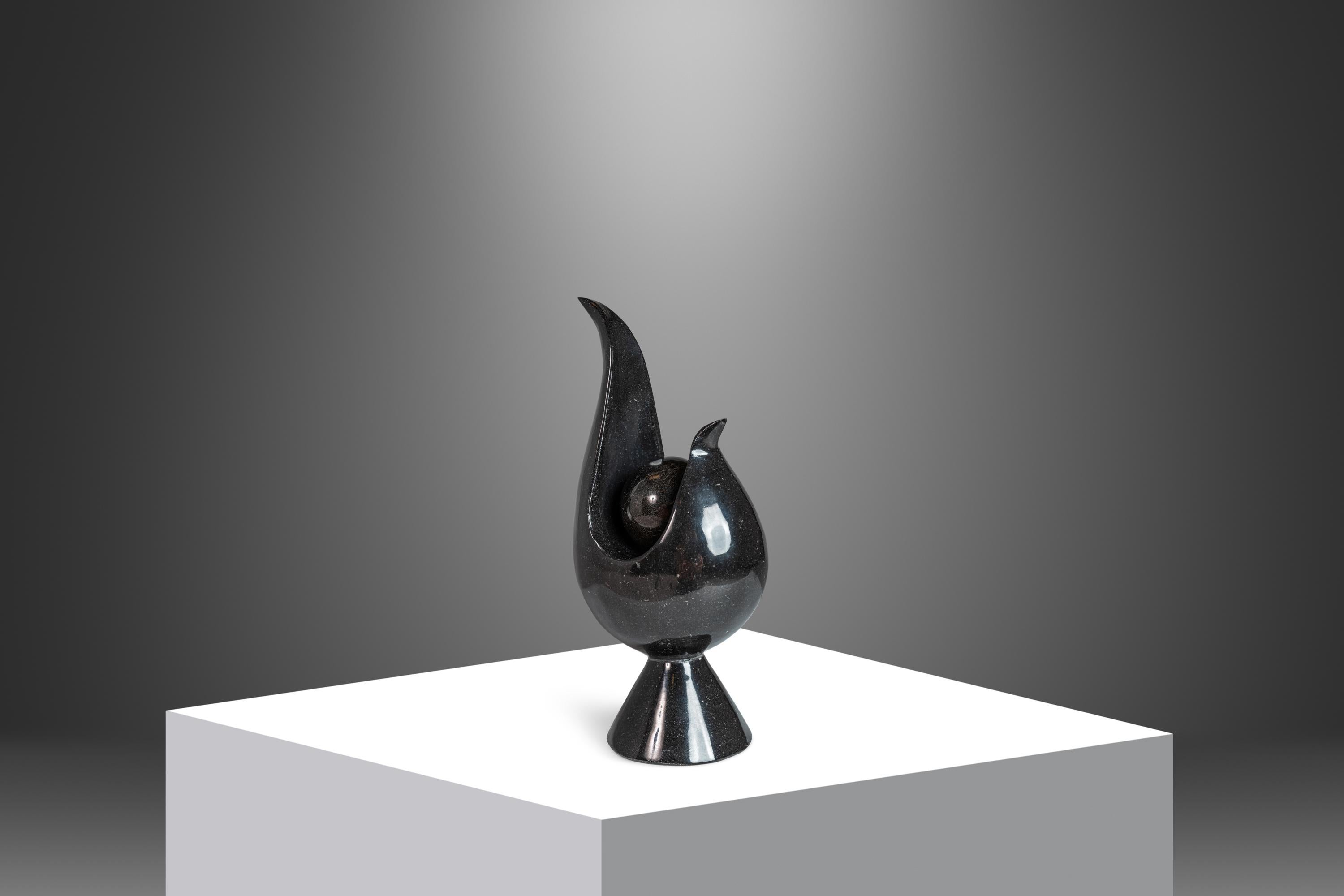 Introducing a fascinating two piece Post Modern sculpture cut from solid black marble and hand-polished to a brilliant shine. Featuring a sphere that rests within the confines of the main sculpture this two-in-one piece is absolutely alluring and