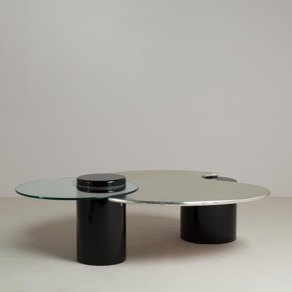 A post modern silver leafed coffee table with jet black lacquered drum bases and rotating circular glass tier 1980s. 
Lacquering carried out by Talisman while the silver leafing has been sympathetically refurbished. 
The silver leaf tier is static