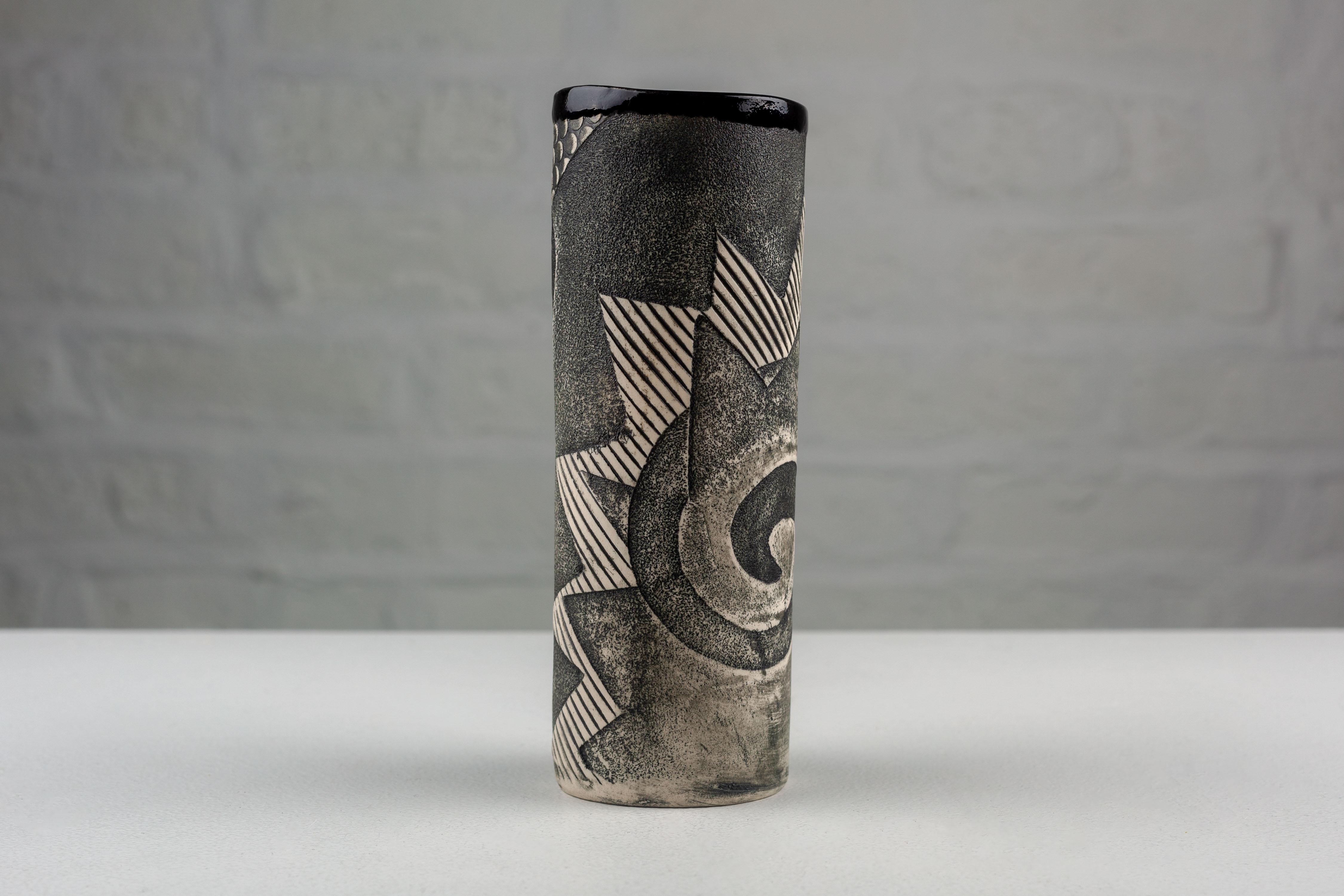Created by Anne Schiesel-Harris and Phillip Harris at ASH WORKS, this 1991 porcelain vase embodies the post-modern design ethos. Its cylindrical form serves as a canvas for a pattern of spirals and zigzag lines, reminiscent of motifs prevalent