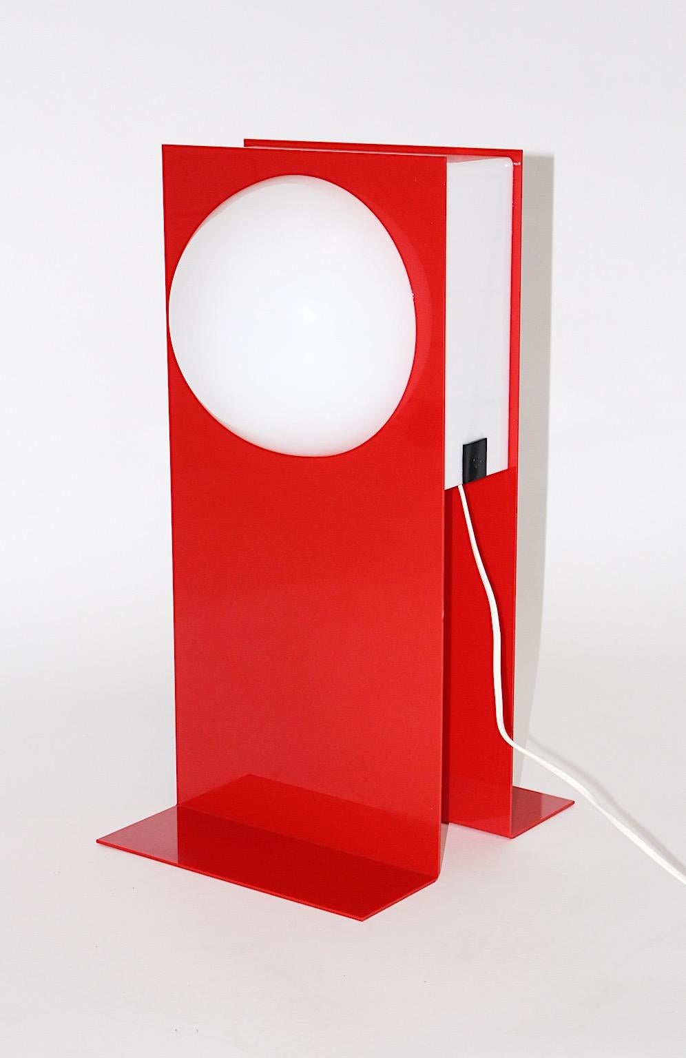 Postmodern style vintage table lamp from plastic in red and white color tones, 1980s.
A beautiful table lamp from plastic shows a signature with the initials HG, probably the initials of the artist. 
The upper part features a white dome on each