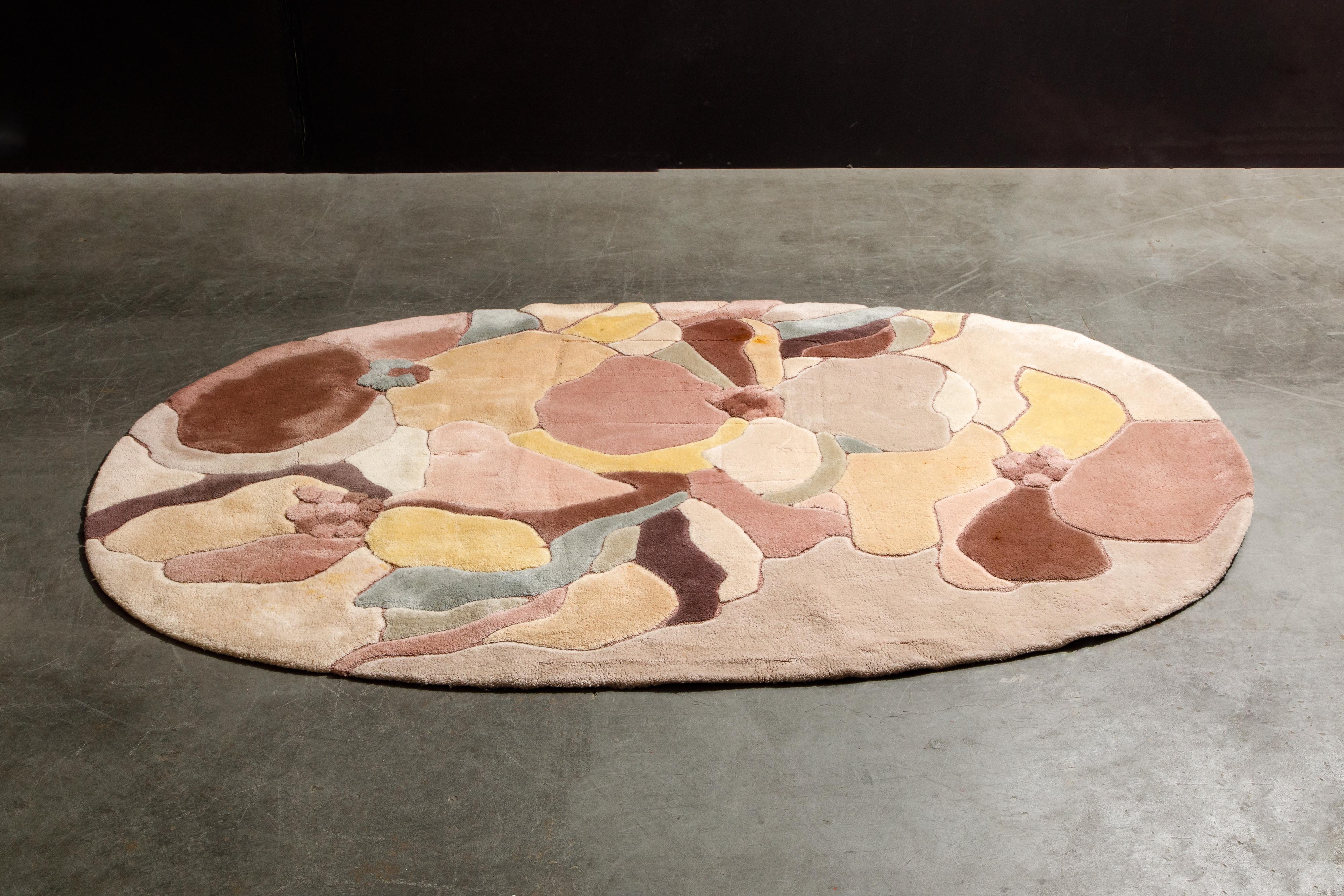 This Post-Modern oval rug by Edward Fields is signed and dated 1984 and made from 100% virgin wool. Featuring abstract shaped of different shades of pink and peach, and measures 109.5
