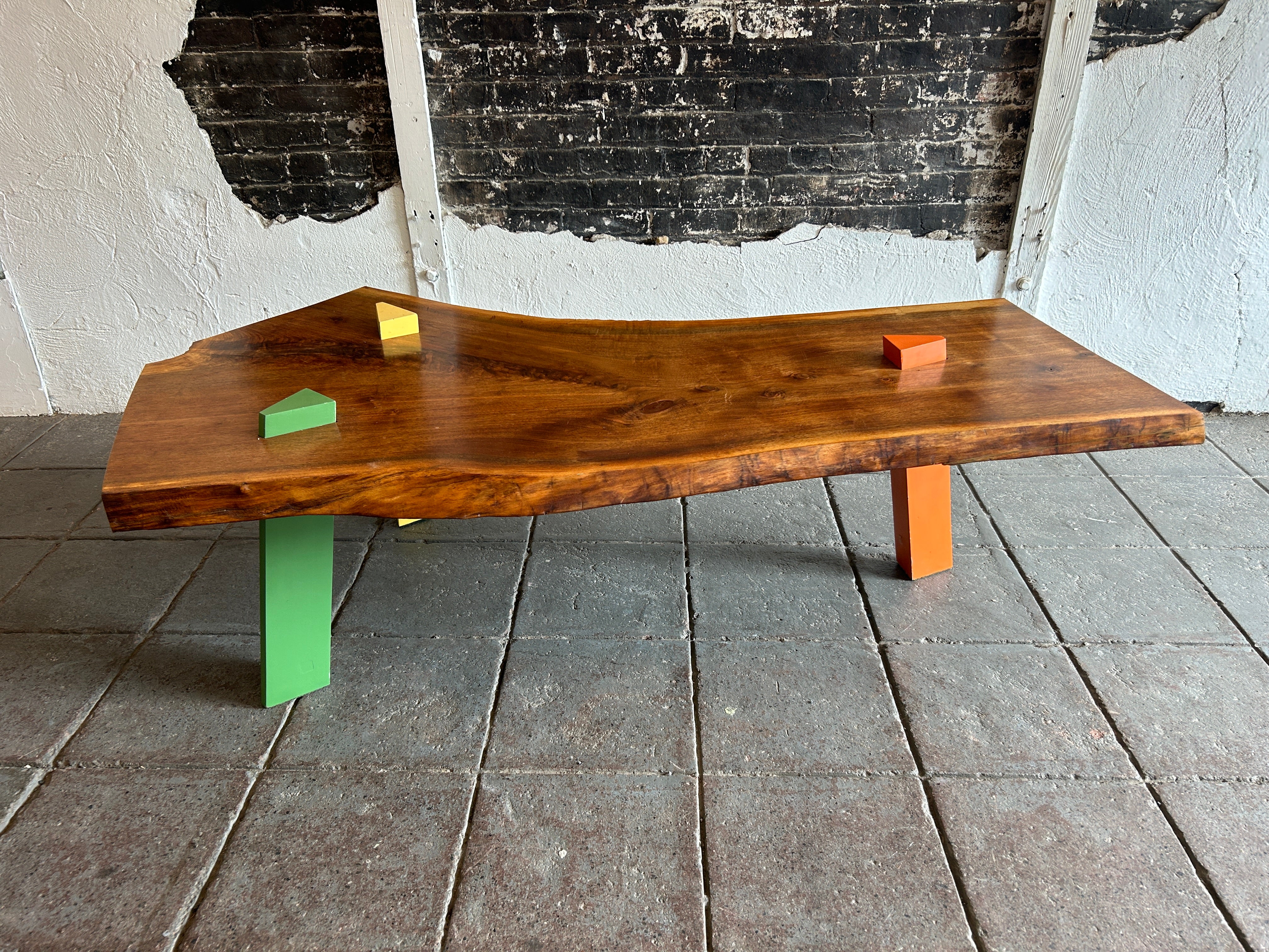Post Modern Walnut Slab coffee table with colored triangle angled legs that protrude through the top slab. studio craft. 2” thick walnut slab top in beautiful condition. Very fun studio craft hand made coffee table or bench. Very heavy and solid