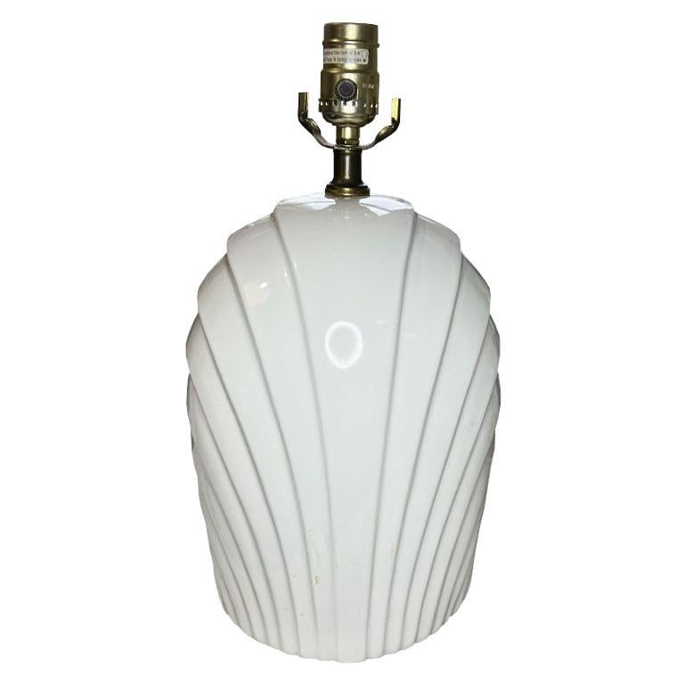 A vintage post-modern white ceramic shell motif table lamp. Glazed in a crisp white ceramic, this light will add interest to any room. The overall shape is more of an oval, wide on the front and back, and skinner in depth. Overlapping trompe l'oeil