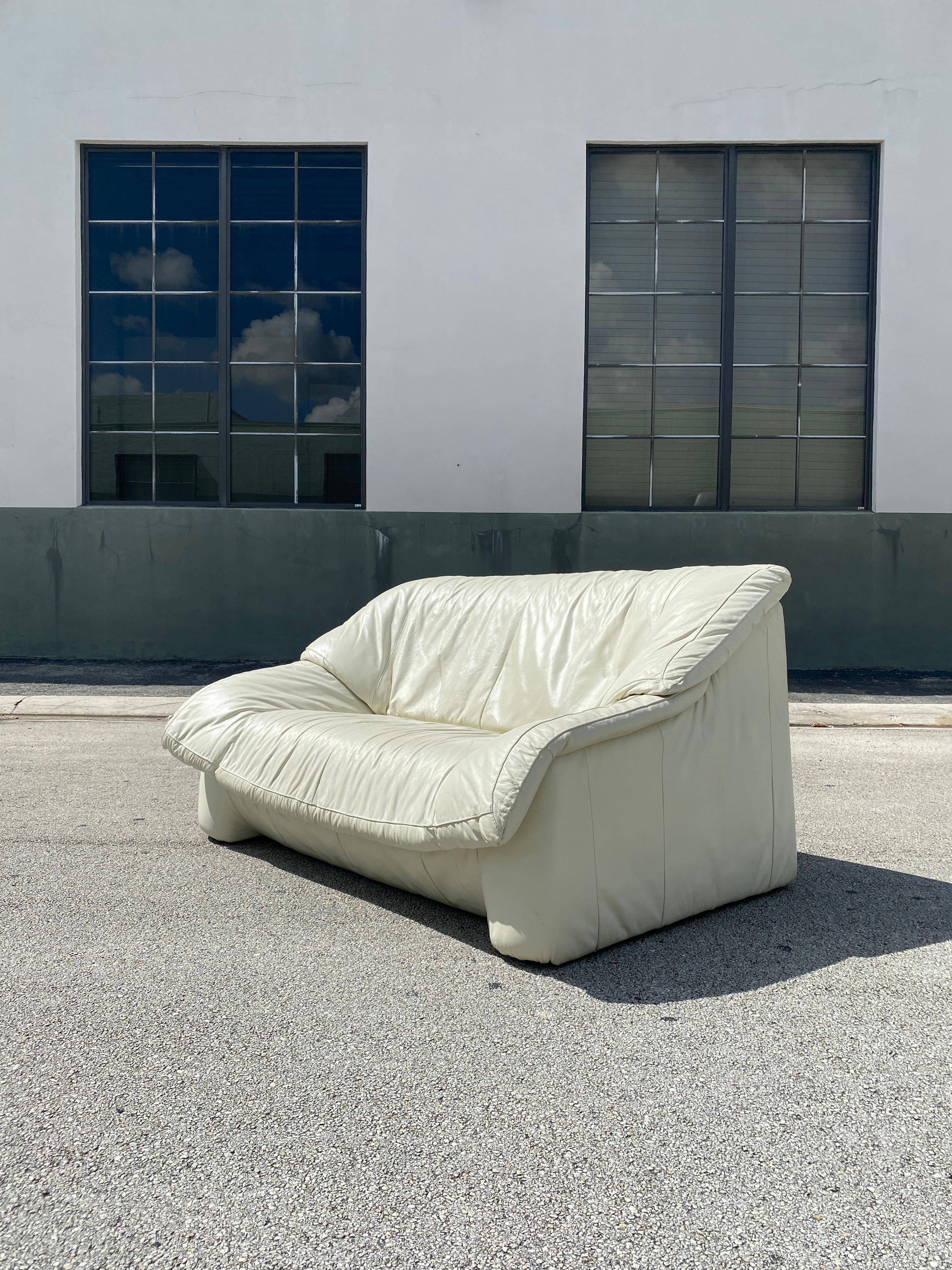 Vintage Post Modern two seater white leather sofa. Features a great semi unstructured form with high quality leather upholstery. In very good vintage original condition with the leather being very good with no holes/tears, and just some minor