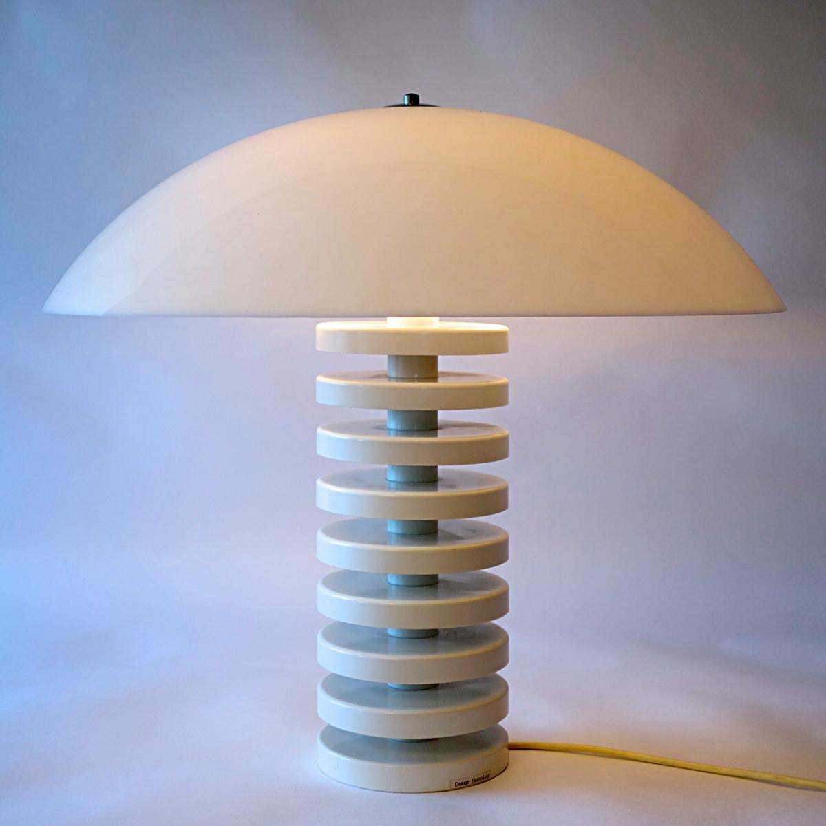 Nine white plastic disks form the base of this stylish, cheerful and very rare table lamp designed by Dutch light master Harco Loor. A large white shade tops it beautifully.
The design is both transparent and very present, making this a wonderful