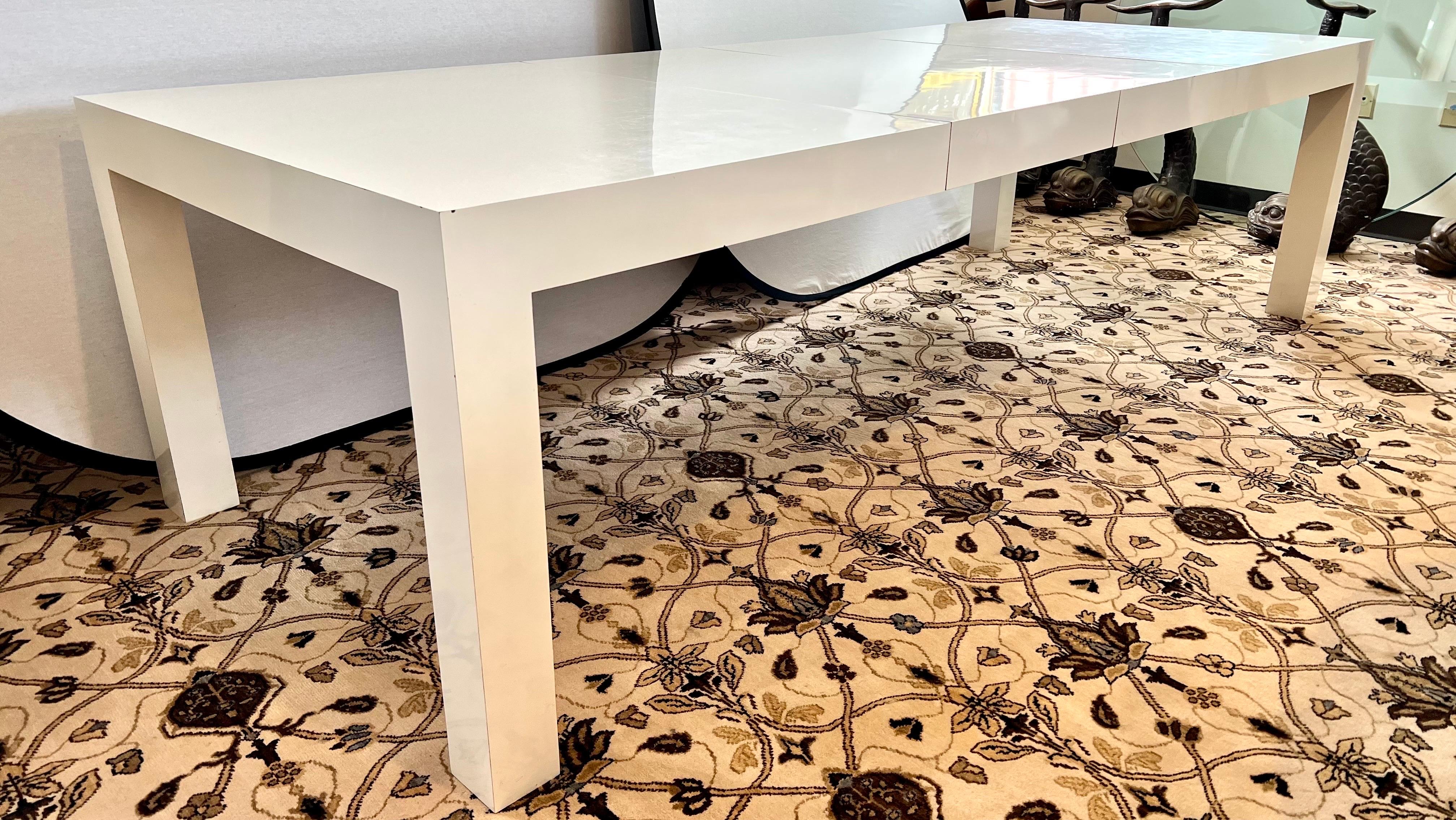 Sleek modern and clean lines characterize this Post-Modern parsons dining table with a glossy white lacquered surface. Extra long size when leaves are inserted. Each leaf is 20