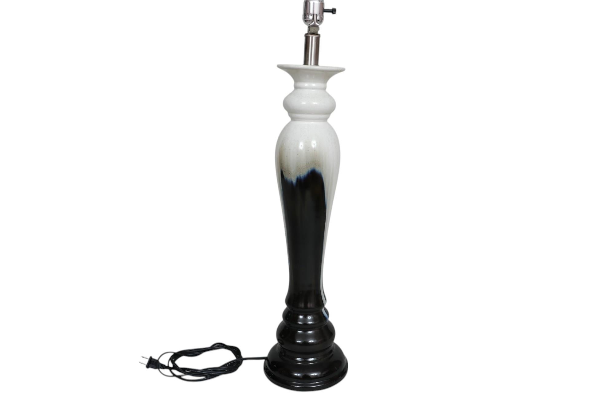 A Post Moderne period drip glaze ceramic table lamp. The tall baluster vase is elegantly turned and glazed with a black drip glazed with blue flame like edges over a speckled cream body.