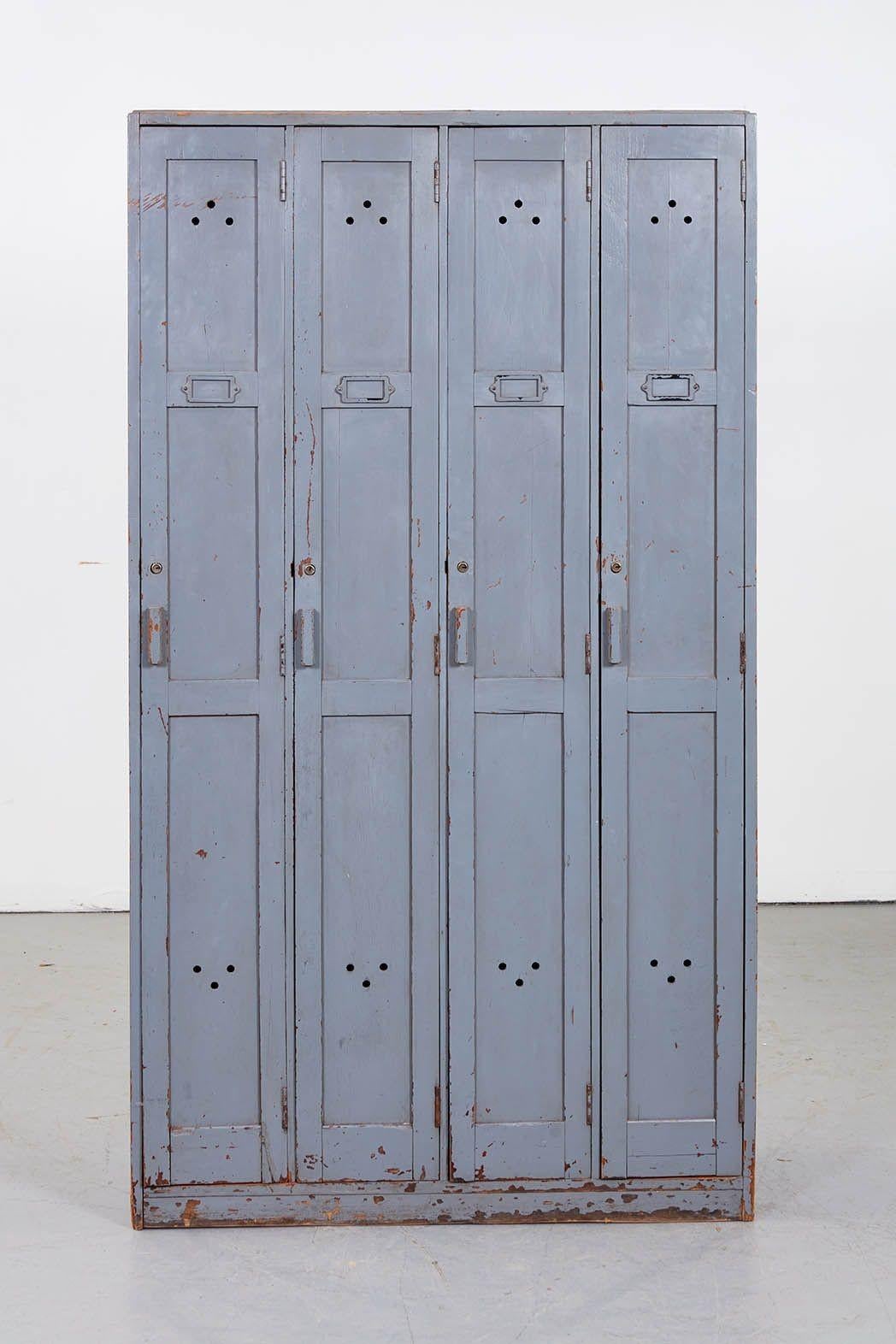 A vintage wooden Post Office locker unit comprising four lockers having paneled doors with wooden handles, locks, name plate holders and air holes. In old Post Office gray paint. Useful narrow proportions. A conversation piece as well as a