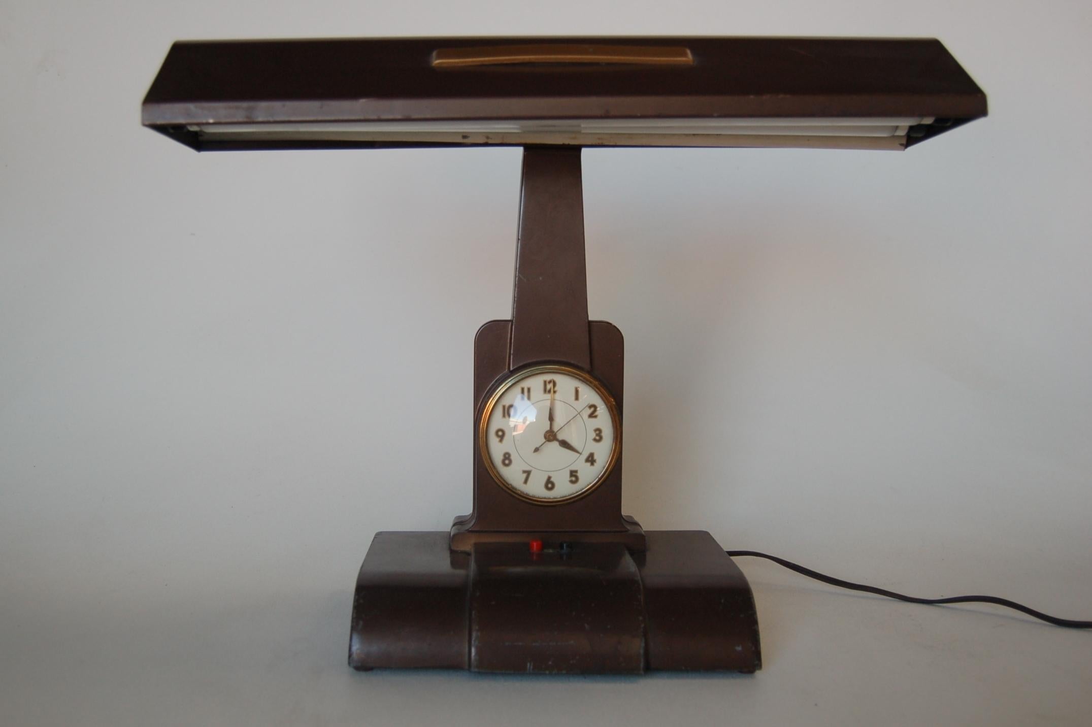 Authentic Art Deco brown hooded fluorescent desk lamp with the clock. The face of the clock reads 