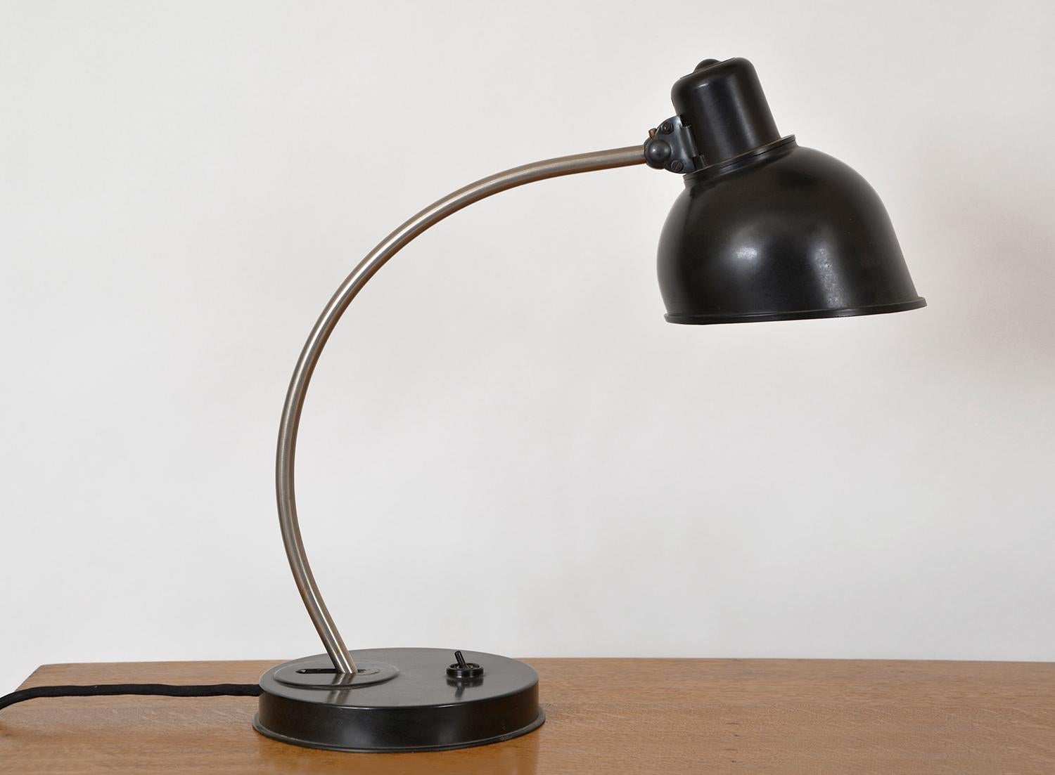 1950s desk lamp designed for Helion VEB Leuchtenbau in the city of Arnstadt, East Germany, unusually with both a Bakelite shade and base, articulated by a brushed steel curved arm. The curved arm adjusts at the base and the lamp shade also pivots on