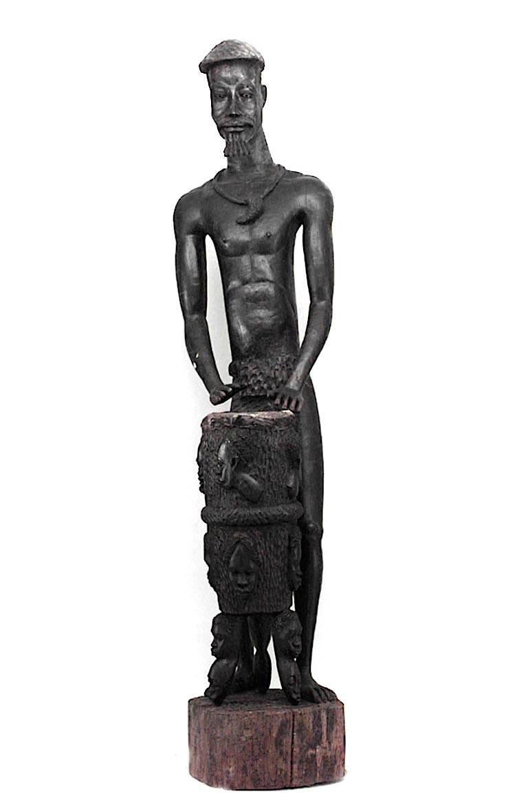 Pair of monumental African ebonized carved tribal figures of man and wife with child and drum standing on a round base (19/20th Cent)(from the World Museum, Tulsa, OK)
