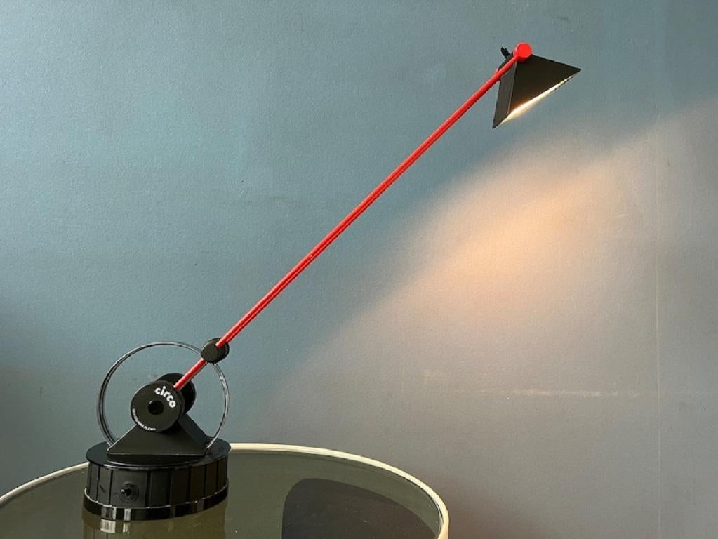 80s Postmodern Circo Table Lamp by Linke Plewa for Brilliant AG. This beautiful red and black piece is incredibly flexible. Not only can the arm be adjusted all over the 'circl'e base, also the base itself can be rotated and the triangular shade