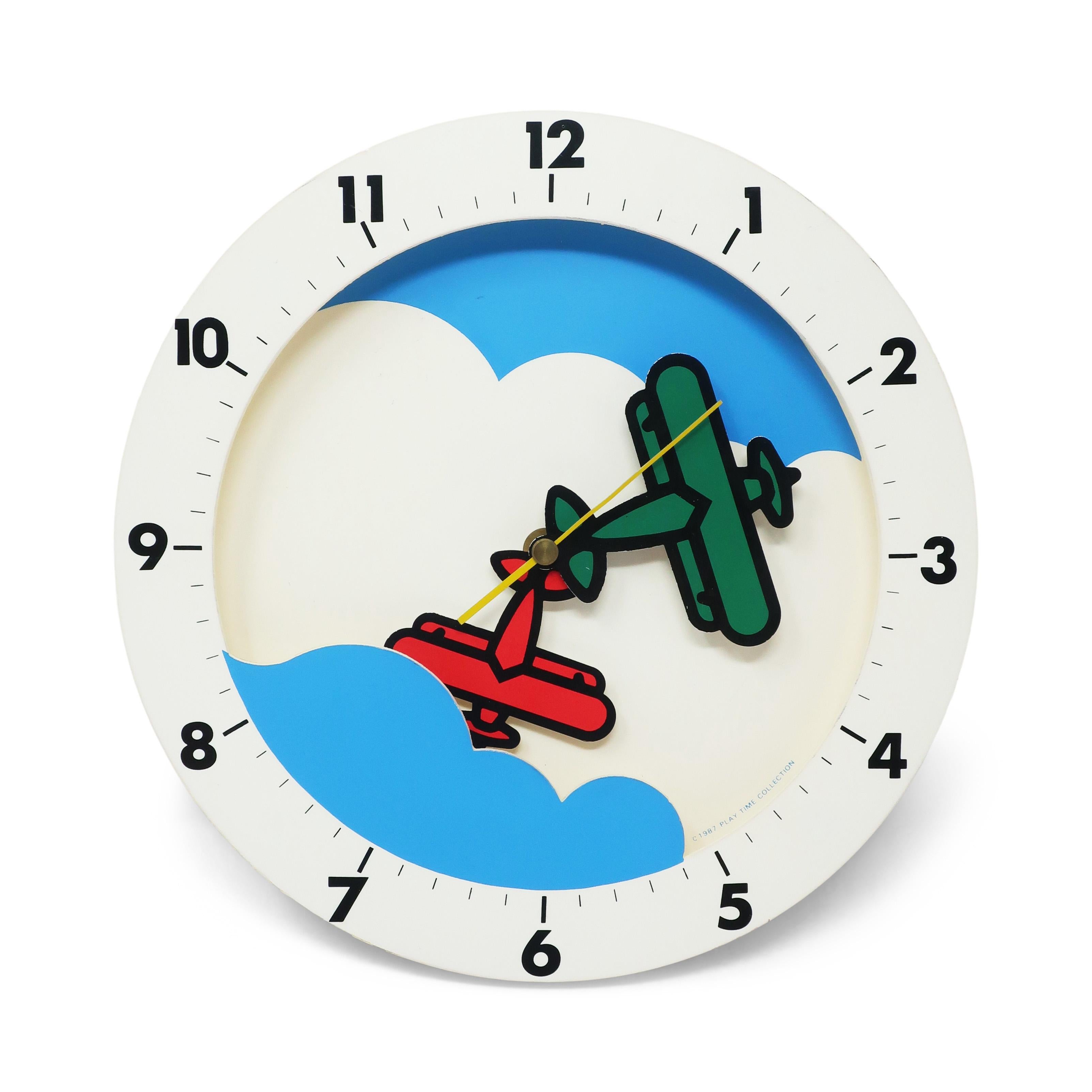 A whimsical postmodern wall clock from Play Time. A 1987 design with blue sky, fluffy white clouds, and a red and a green airplane as hands to tell them time.

In good vintage condition with wear consistent with age and use. Marked with
