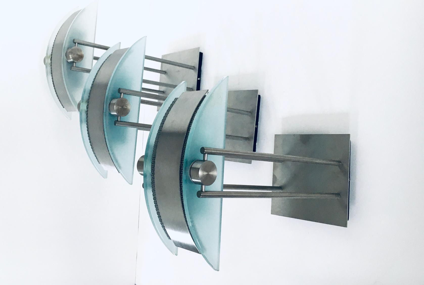 Ensemble de 3 appliques postmodernes de Moonlight Design, fabriquées en Belgique dans les années 1990. Applique halogène set de 3 lampes. Base en métal brossé avec verre dépoli en forme de demi-lune et tôle perforée fabriquée à la machine. Vous
