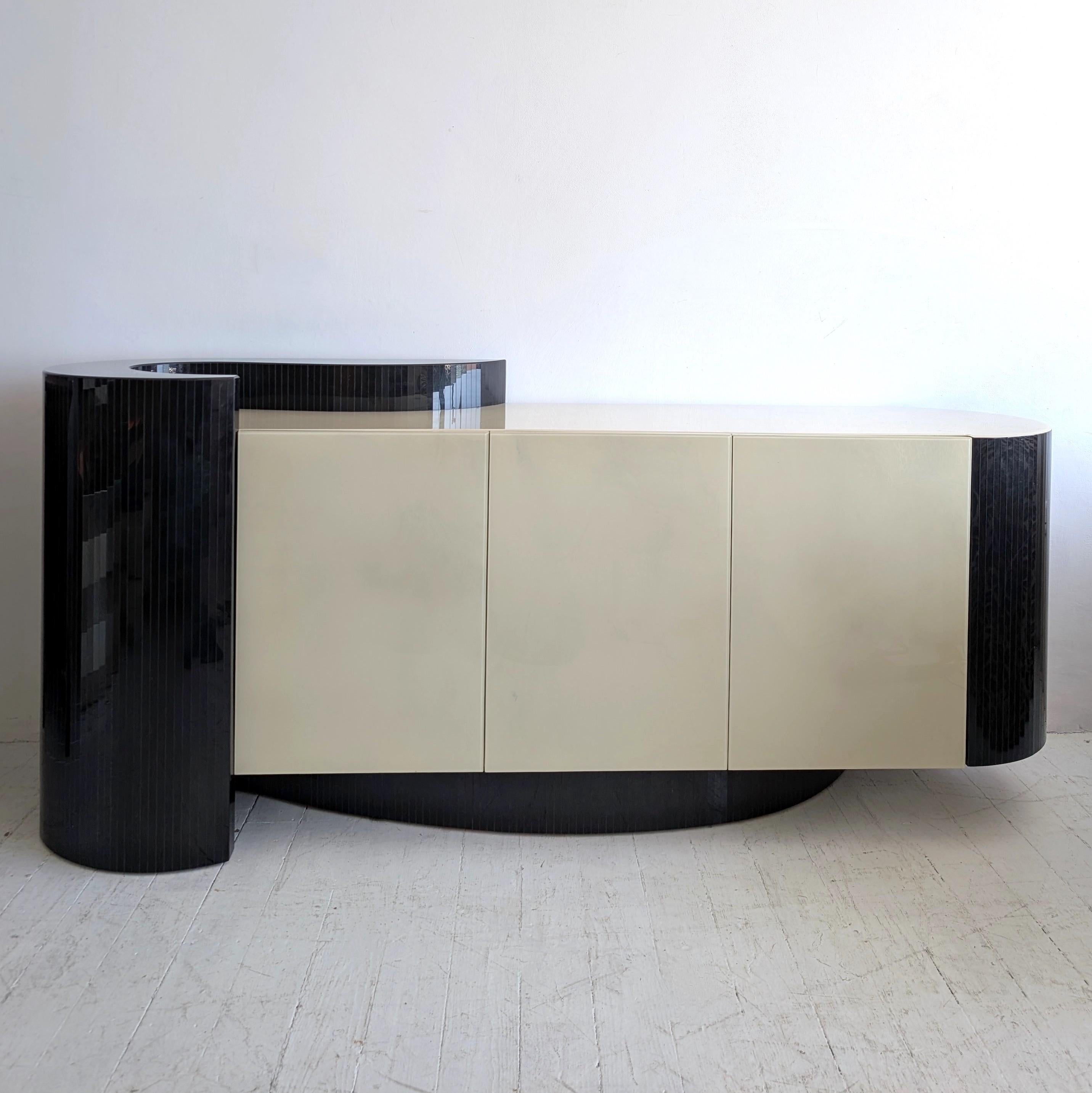Questa splendida credenza asimmetrica postmoderna / deco revival è molto simile allo stile di Karl Springer, ma non ho informazioni sul produttore o sul designer - potrebbe essere stato un pezzo su misura. 
Ante rivestite in resina color crema