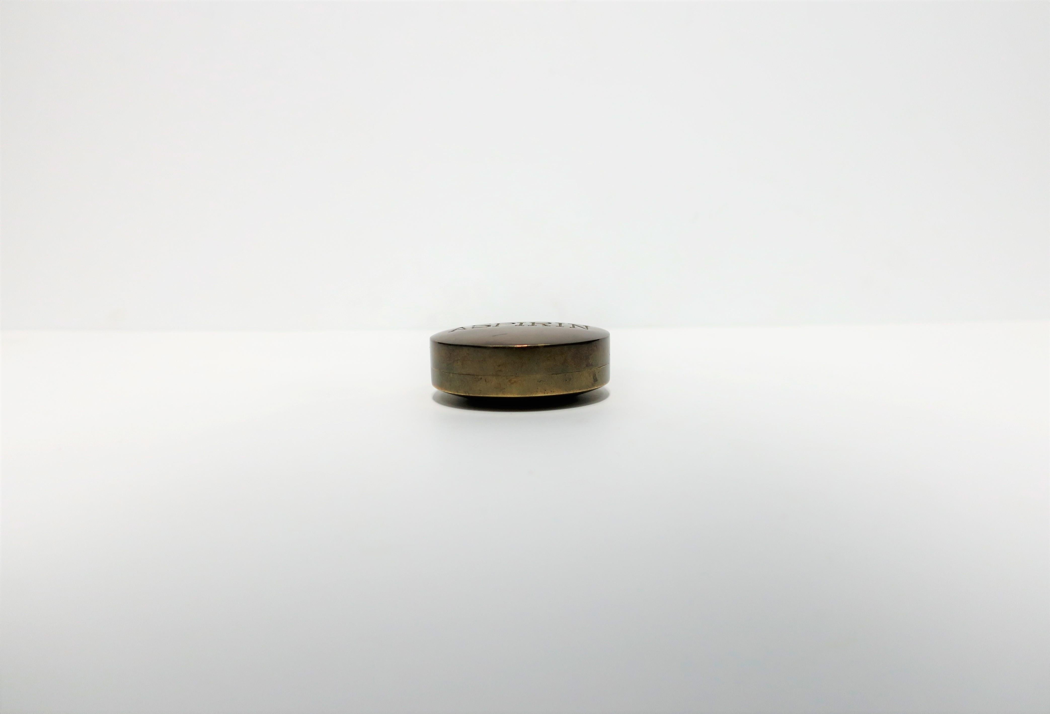 A substantial round Post-Modern 'ASPIRIN' brass box, 20th century, circa 1970s. Box is an oversized 'aspirin' in solid hand-cast brass and embossed on top in all caps is the word 'ASPIRIN'. A great piece representative of the Post-Modern period,