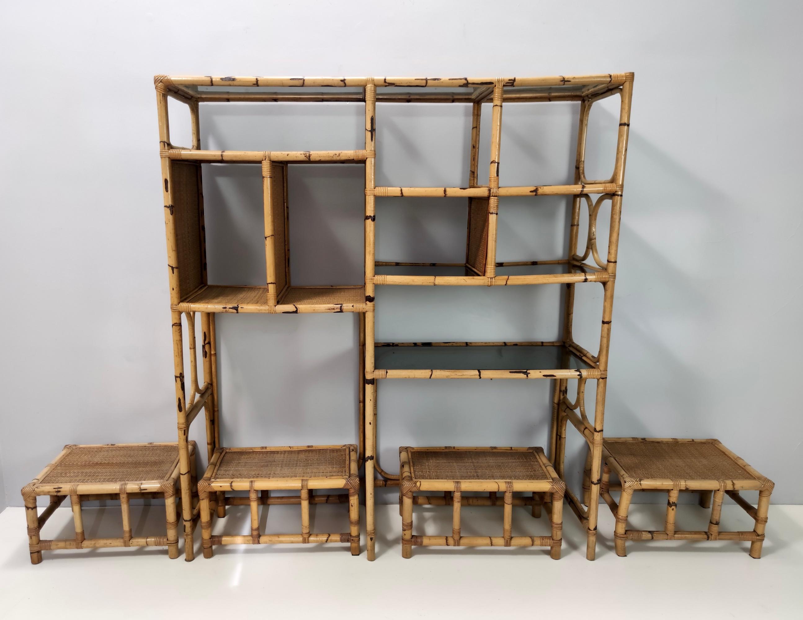 Made in Italy by Vivai del Sud, 1970s. 
The bookcase features a bamboo frame and smoked glass shelves.
This set includes 4 bamboo and wicker stools. 
They might show slight traces of use since they'revintage, but they can be considered as in very