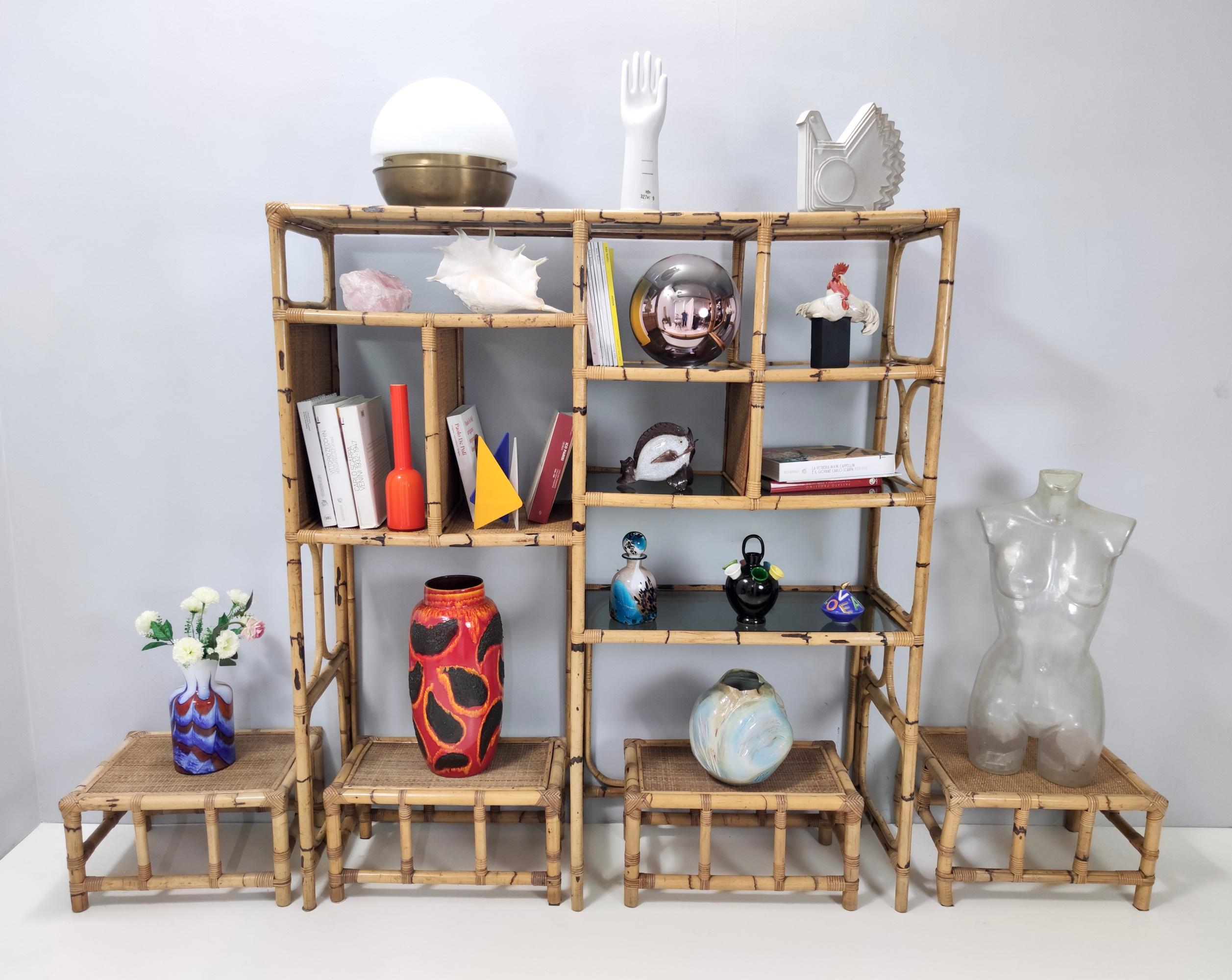 Made in Italy by Vivai del Sud, 1970s. 
The bookcase features a bamboo frame and smoked glass shelves.
This set includes 4 bamboo and wicker stools. 
They might show slight traces of use since they'revintage, but they can be considered as in very