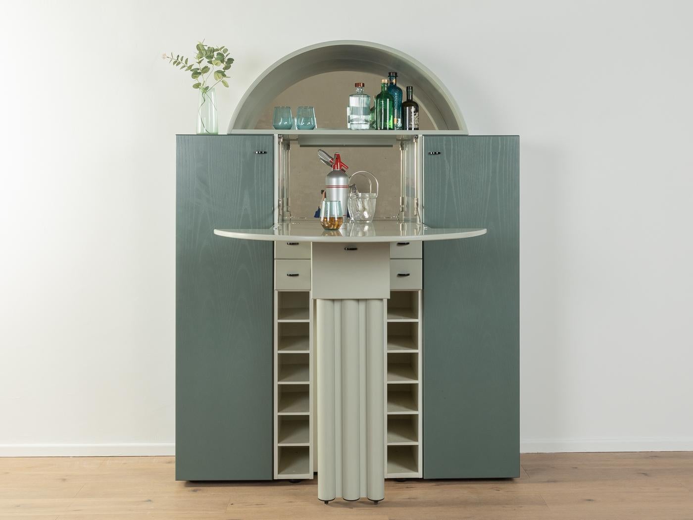 Postmodern three-part bar cabinet by Peter Maly for the Duo-series from Interlübke from the 1980s. Corpus consisting of two side cabinets in petrol stained ash veneer and a grey bar element in the middle with two doors, a folding door, two mirrors,