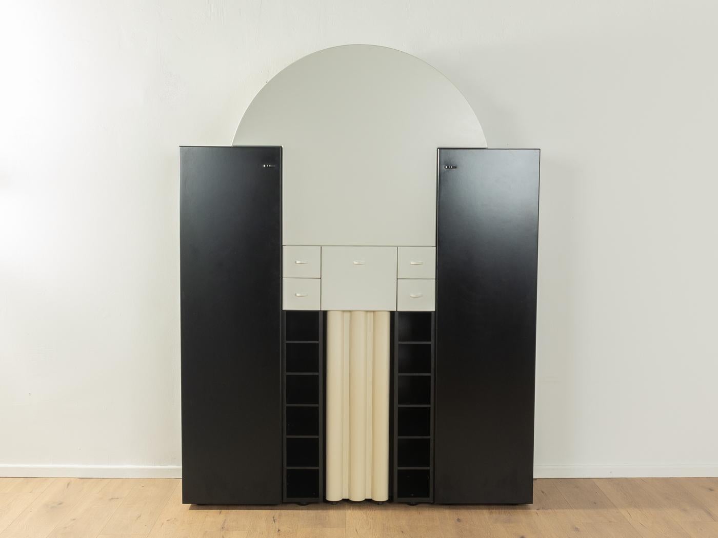 Mueble bar postmoderno de tres cuerpos de la serie DUO de Peter Maly para Interlübke de los años 80. Corpus formado por dos armarios negros con una puerta y tres estantes cada uno y un elemento de barra blanco con una puerta batiente, dos espejos,